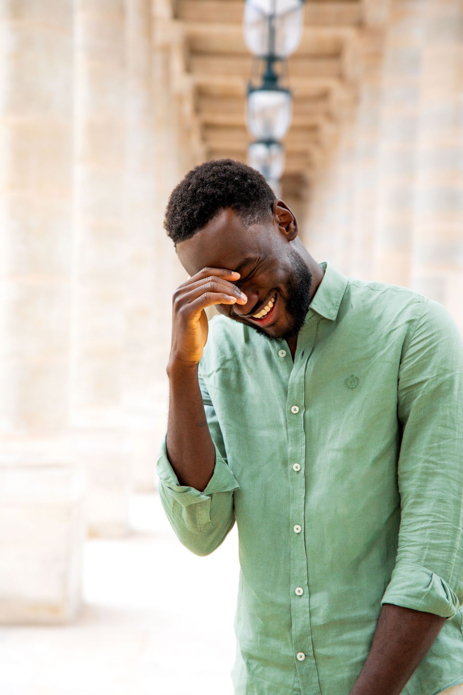 Person in mint green linen button-down shirt expressing frustration with hand gesture against light background.