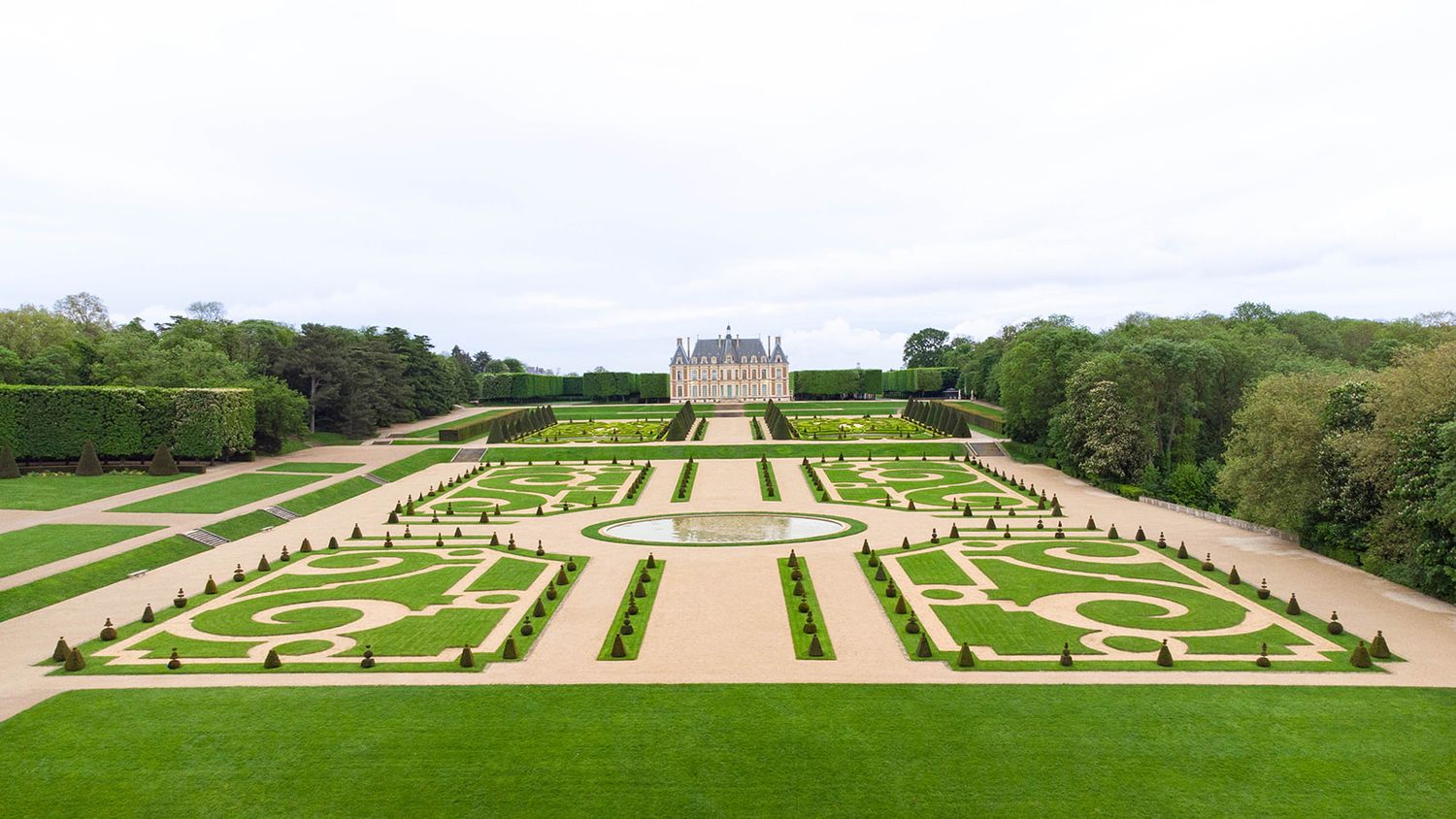 Aerial view of formal French garden with symmetrical landscaping and pathways.