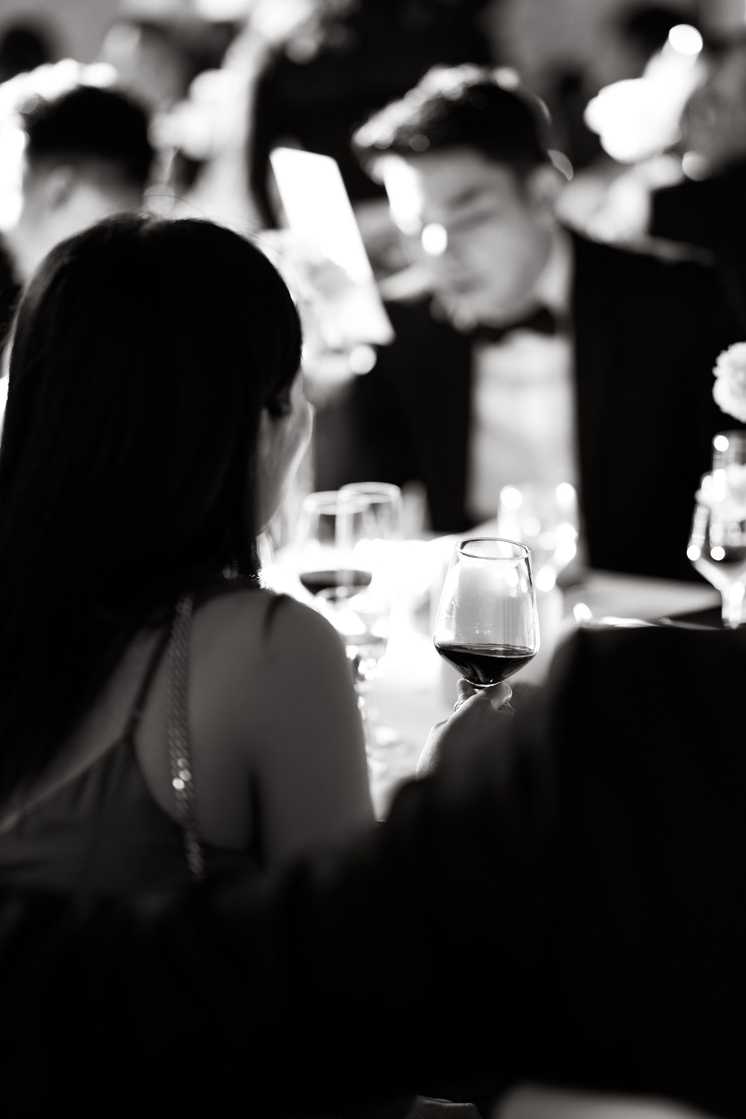 Candid black and white photo of guests dining at an elegant evening event.