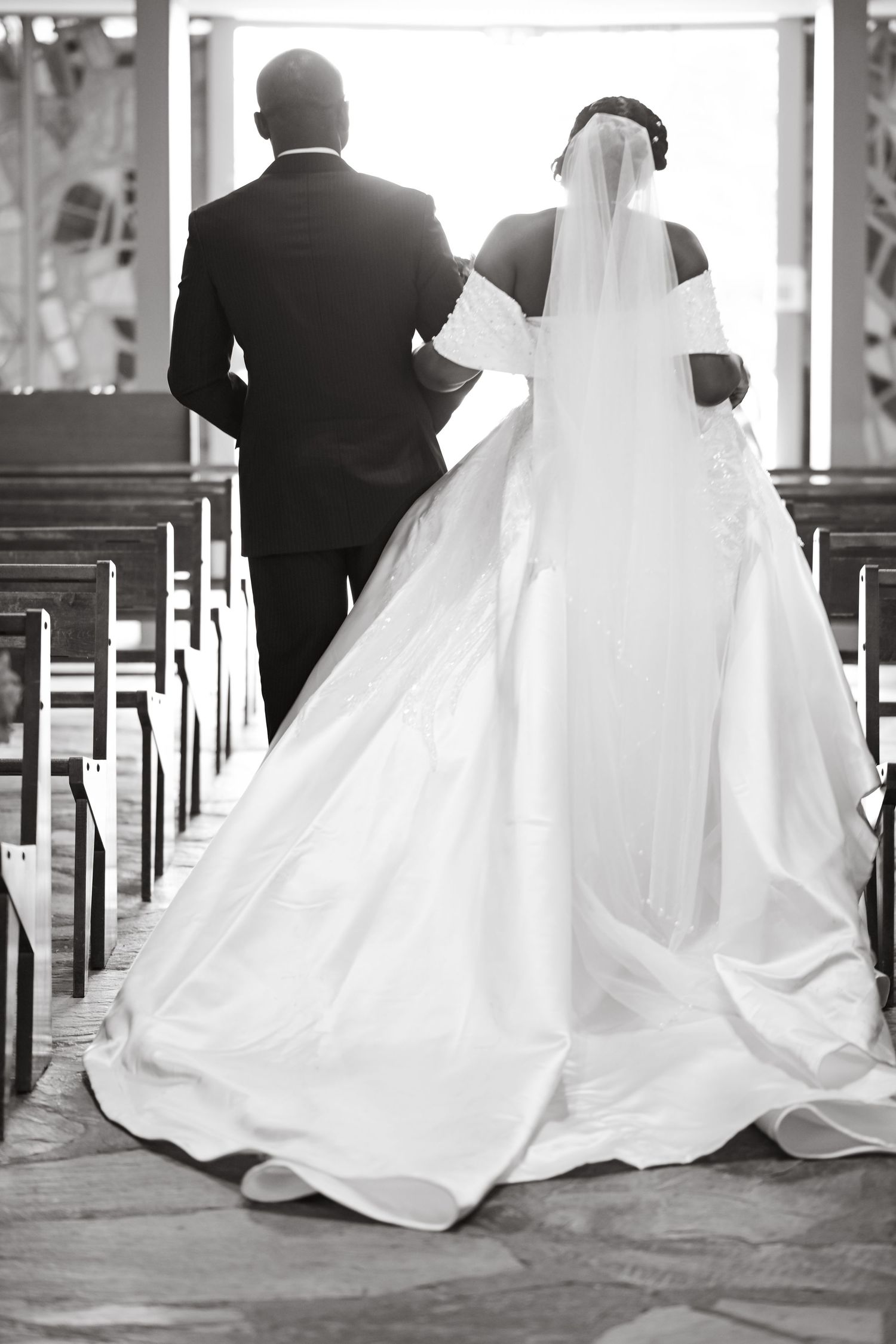 Black and white photos of wedding dress train flowing through church pews.