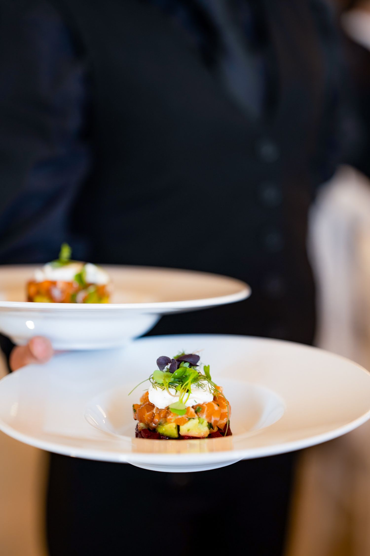 Elegantly plated appetizer on white dish being served at formal event.