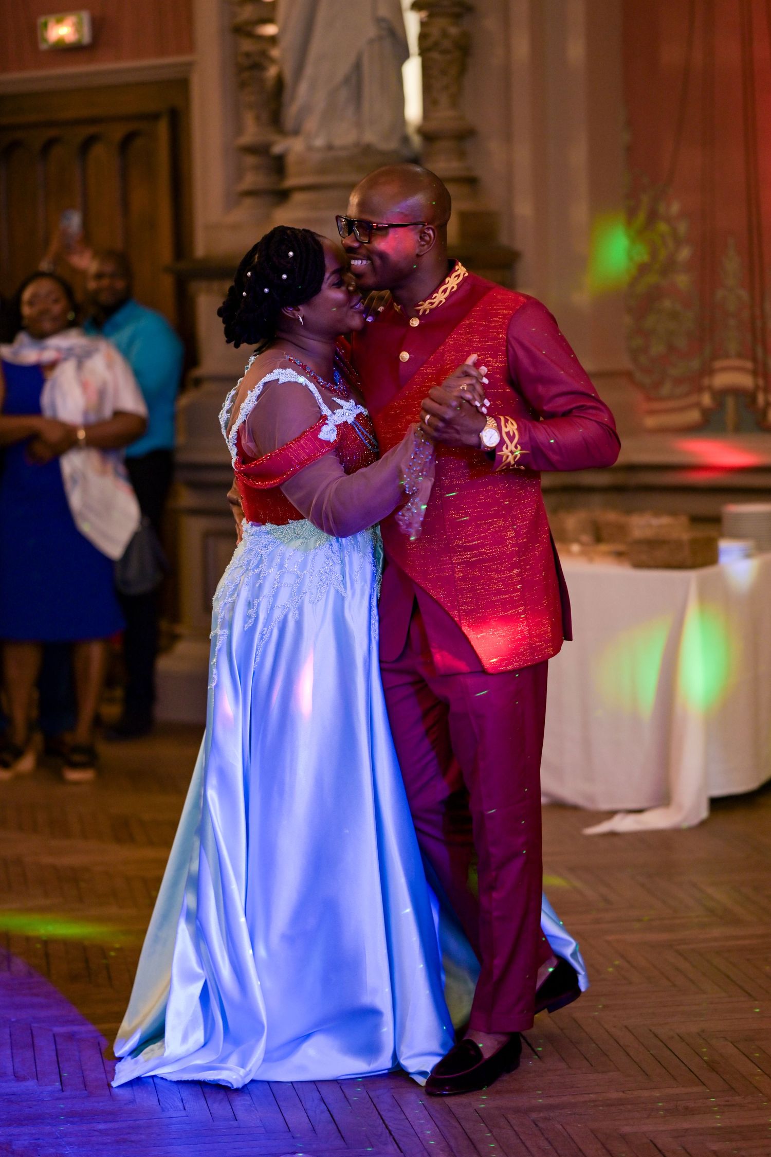Dancers in formal attire performing on a ballroom floor with colorful lighting.