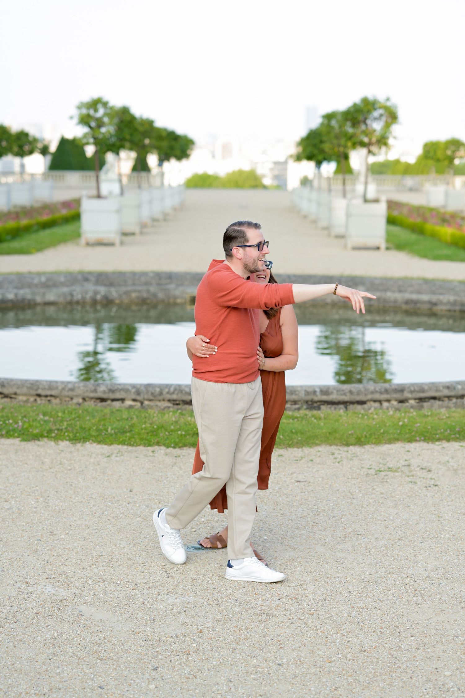 A couple performs dance moves on gravel path near waterfront.
