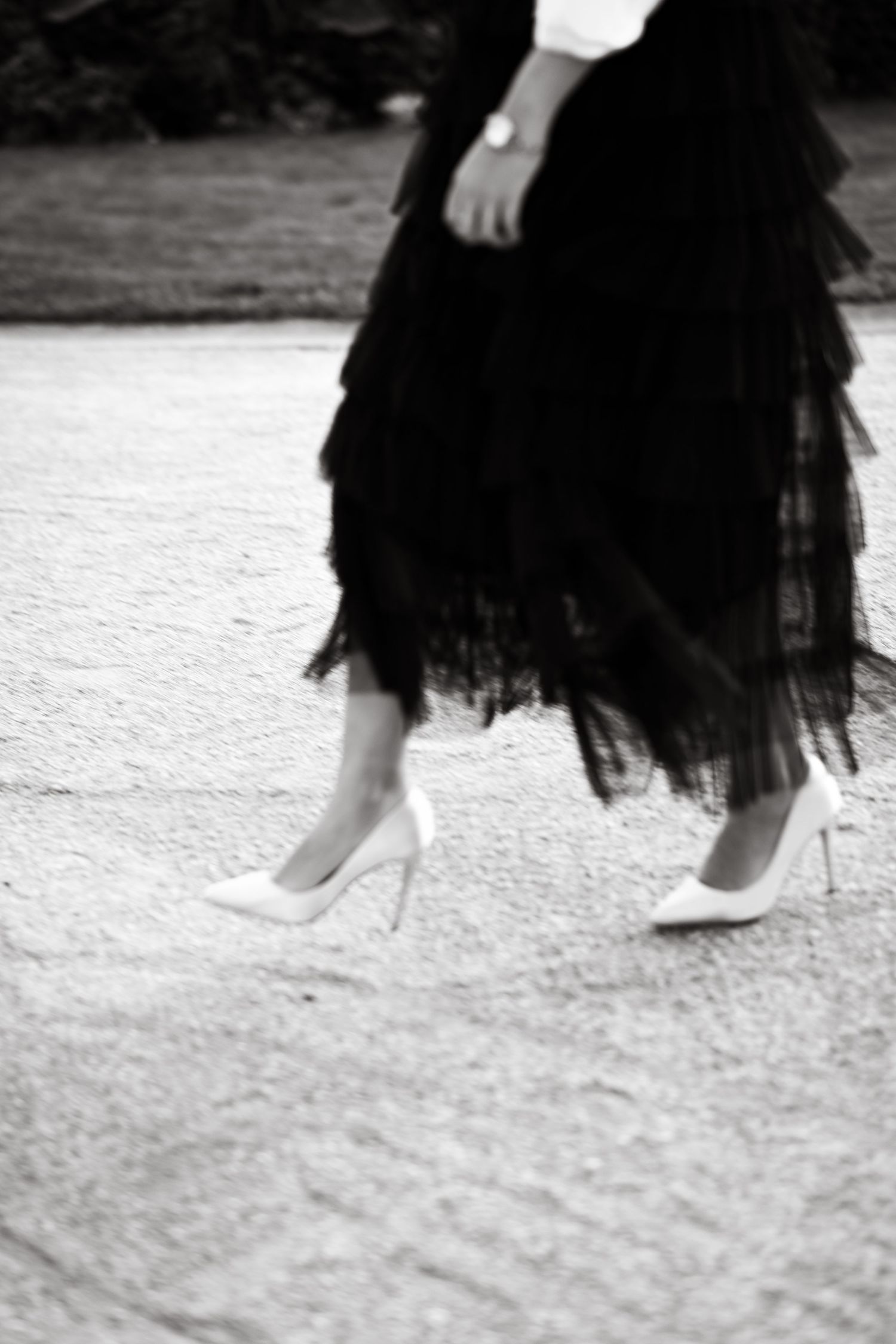 Black and white photo focusing on flowing tulle skirt movement against stone ground.