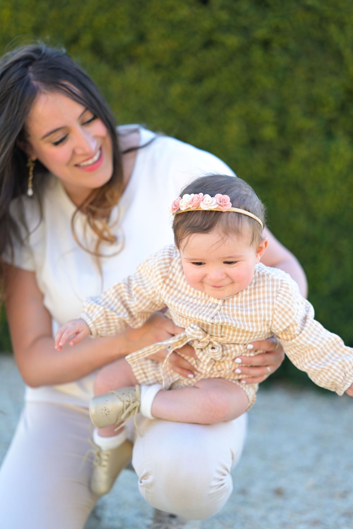 Playful outdoor photo session showing loving family interactions against green foliage.