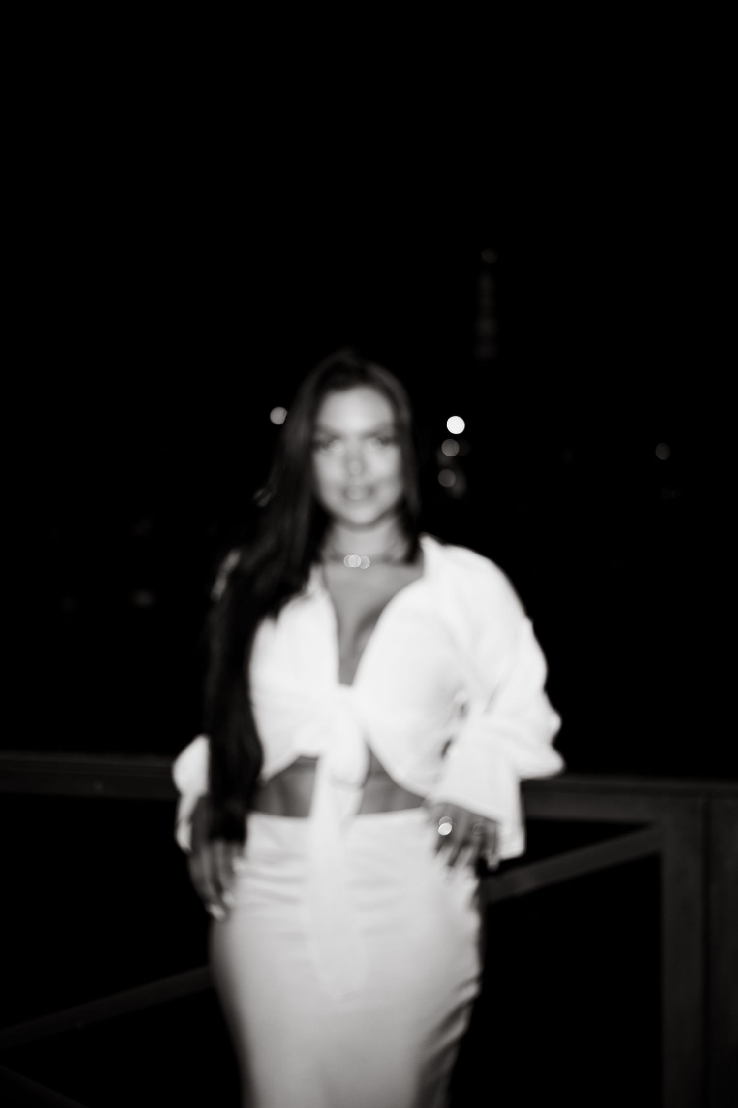 A black and white nighttime portrait of someone in a white outfit against a dark background.