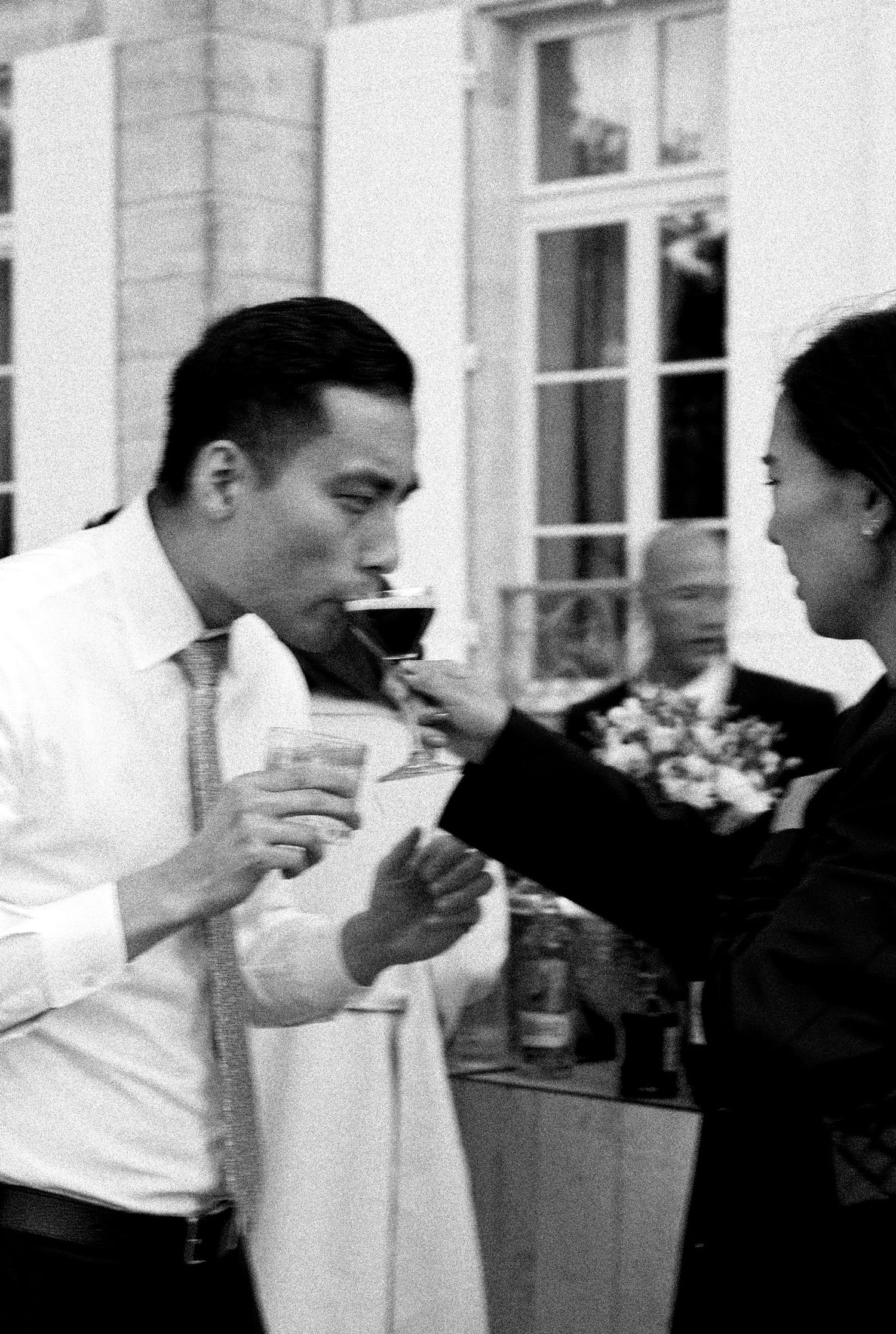 Black and white photo of two people sharing drinks at an elegant event.