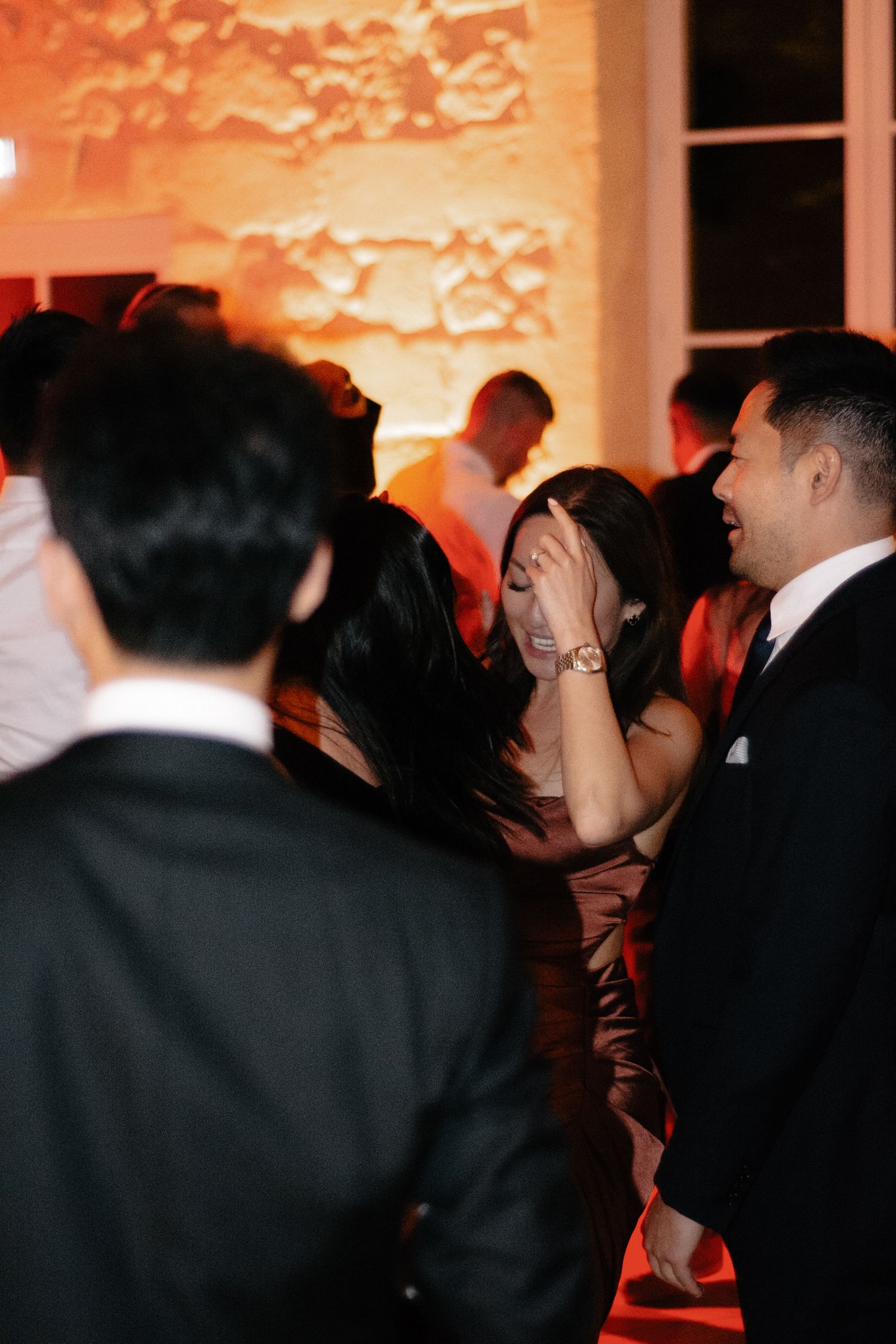 Wedding guests dancing and celebrating under warm ambient lighting.