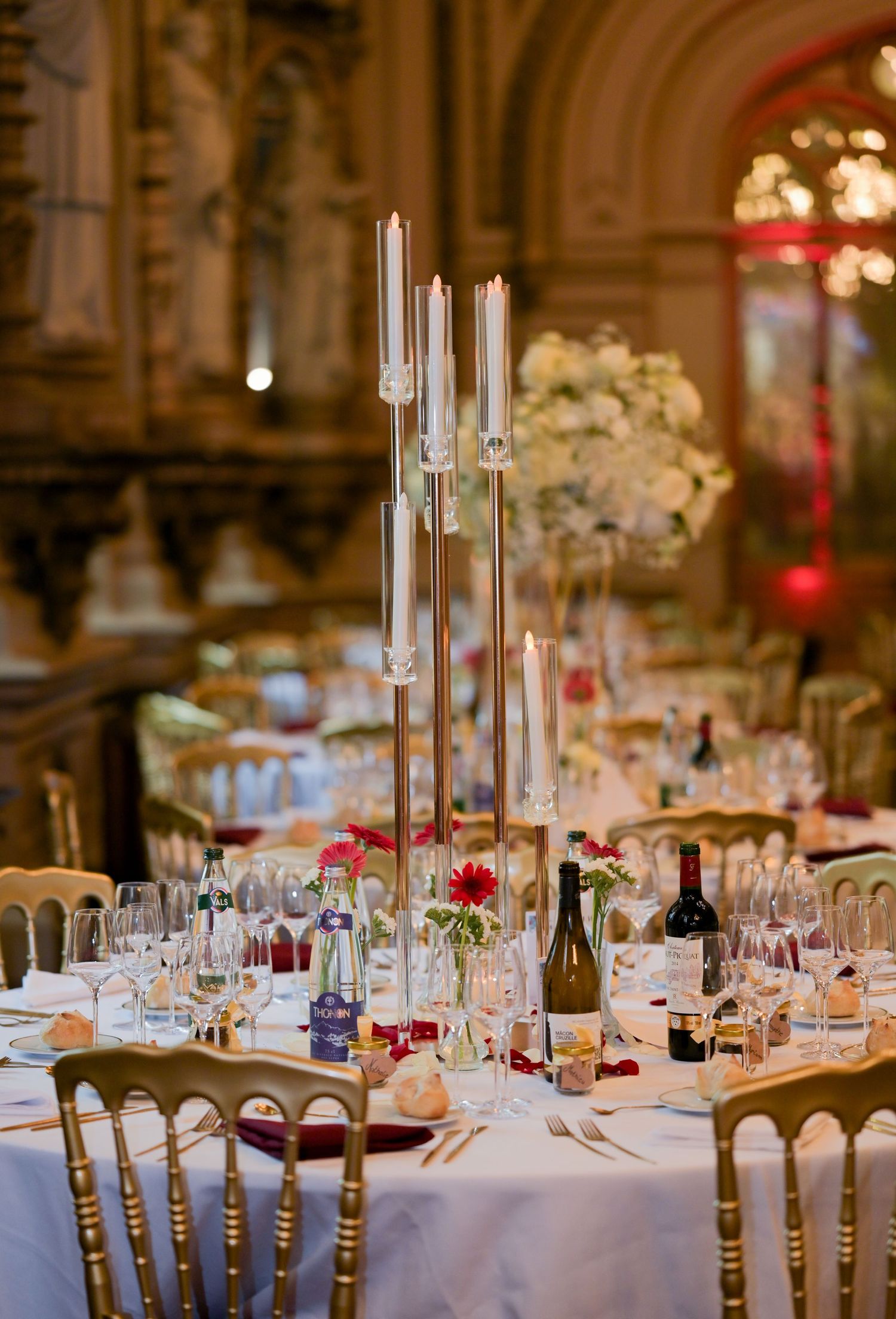 Formal table settings with tall glass candleholders and white floral arrangements.