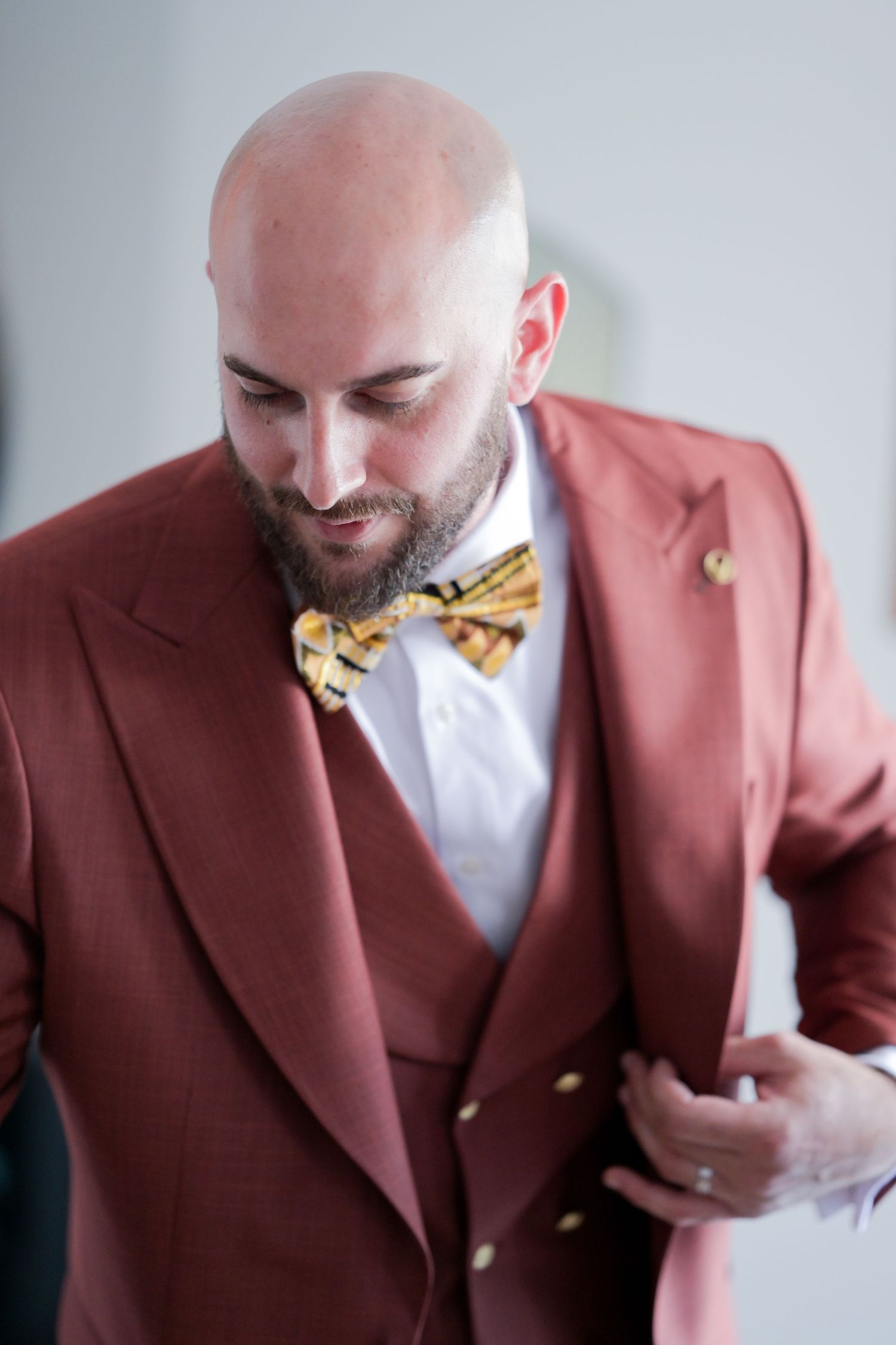 Person in burgundy suit jacket laughing and looking down.
