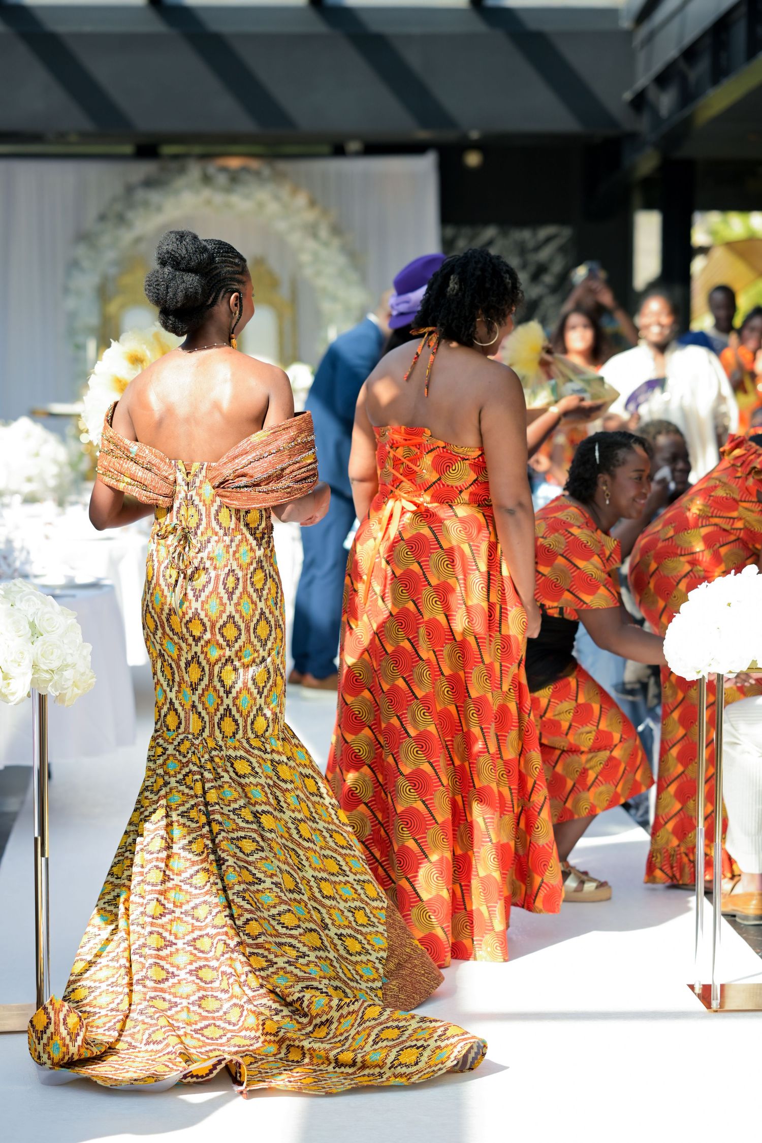 People wearing colorful African print dresses at a formal event.