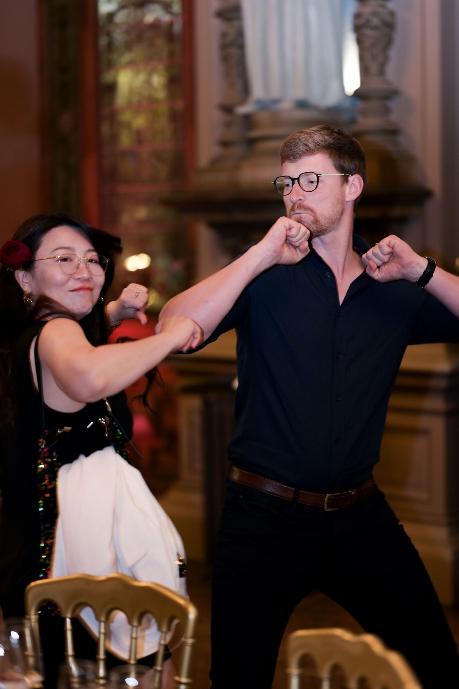Two people dancing energetically in an elegant ballroom setting.