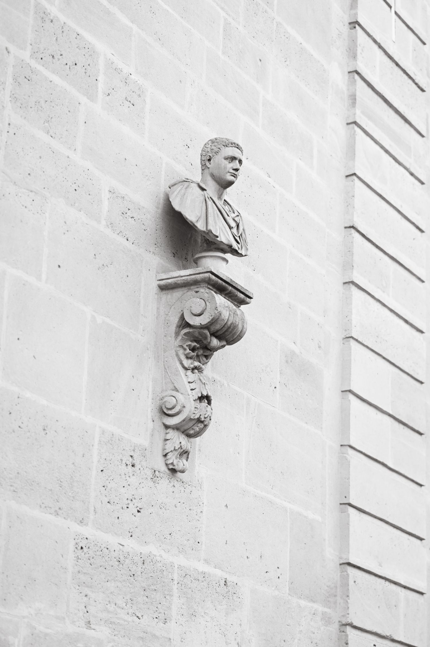 Classical stone architectural details showing decorative busts mounted on a light colored wall.