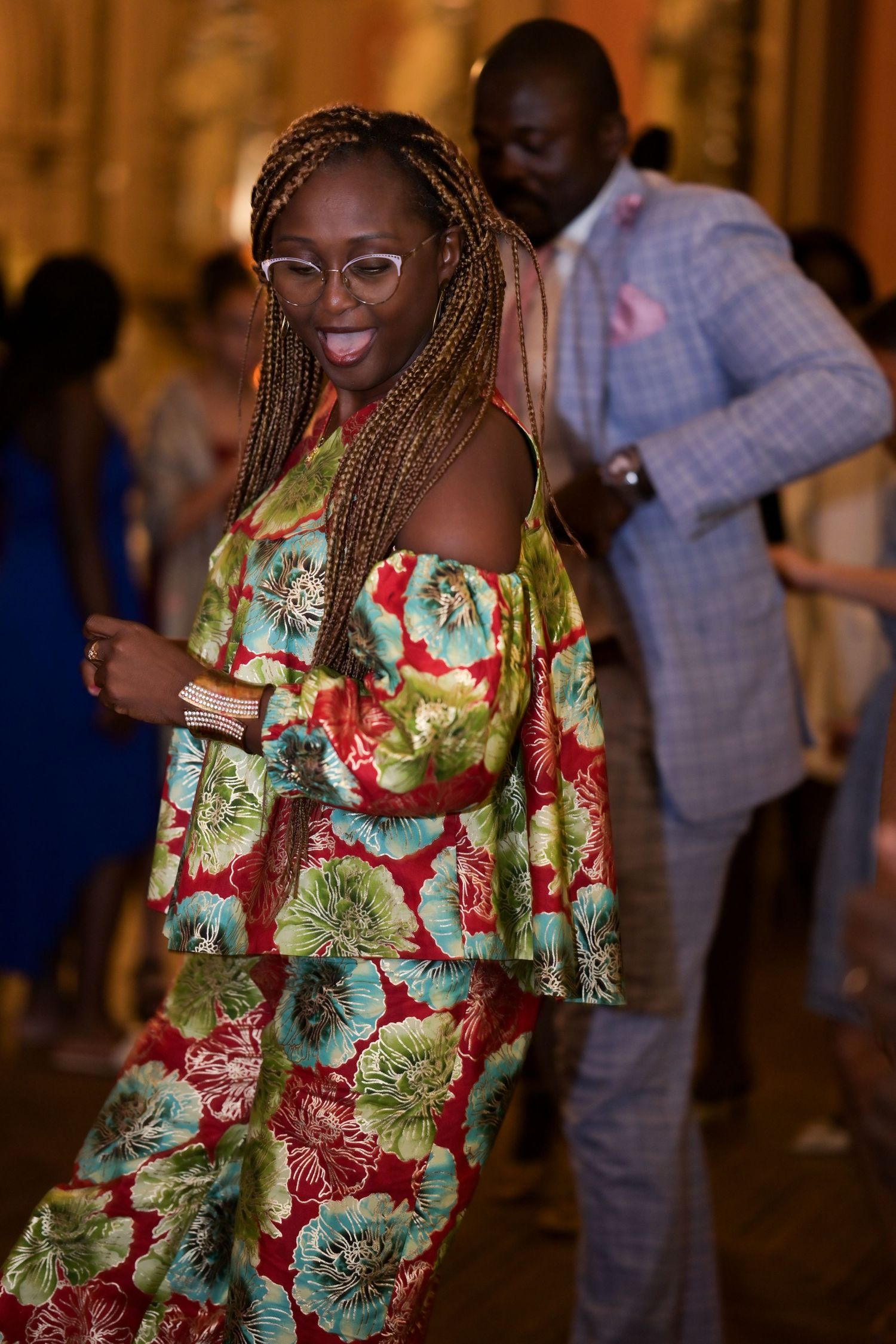 Person wearing vibrant floral print dress dancing at an indoor celebration.