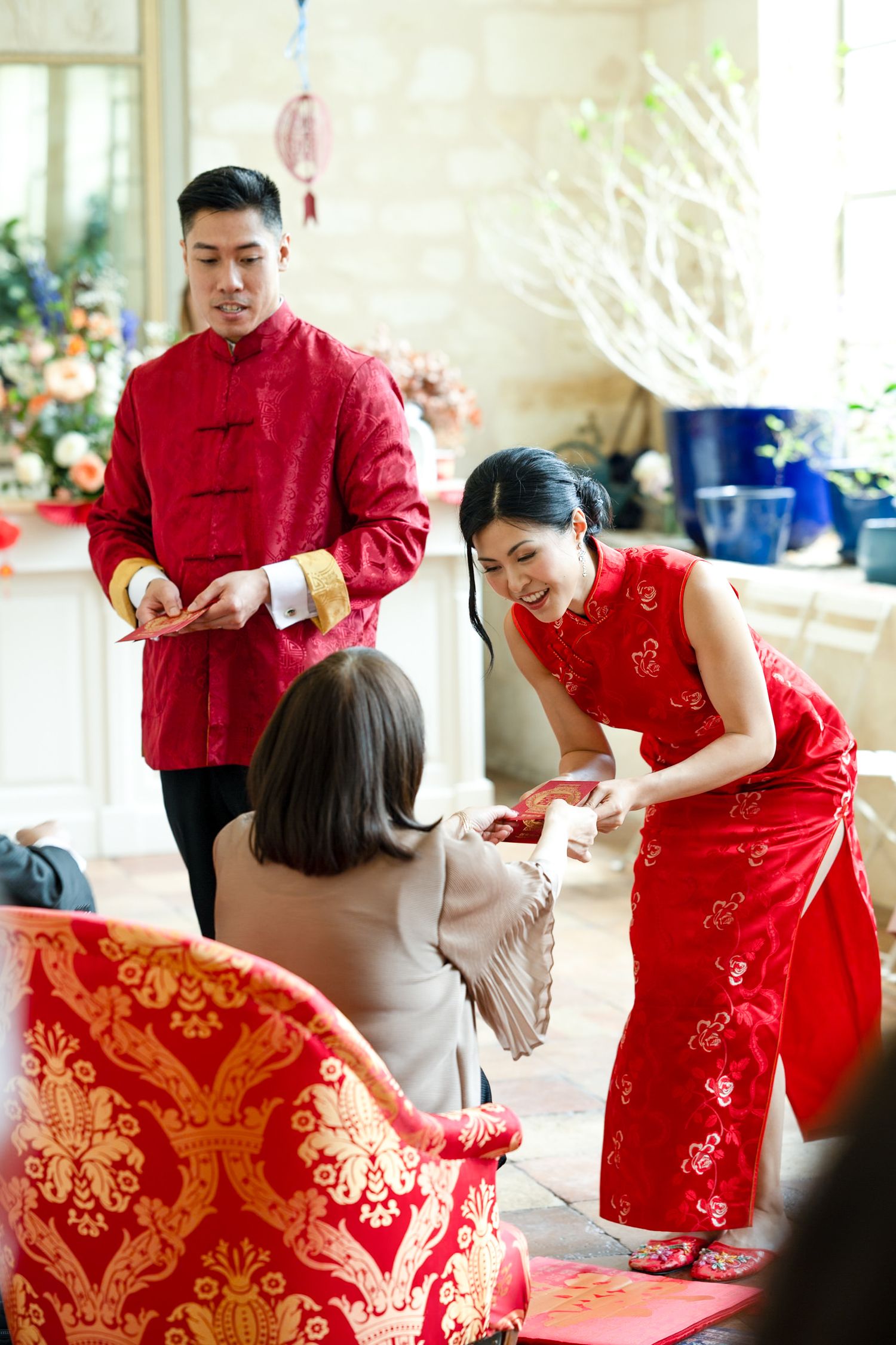 Traditional Chinese tea ceremony with couple in red attire serving tea to family.