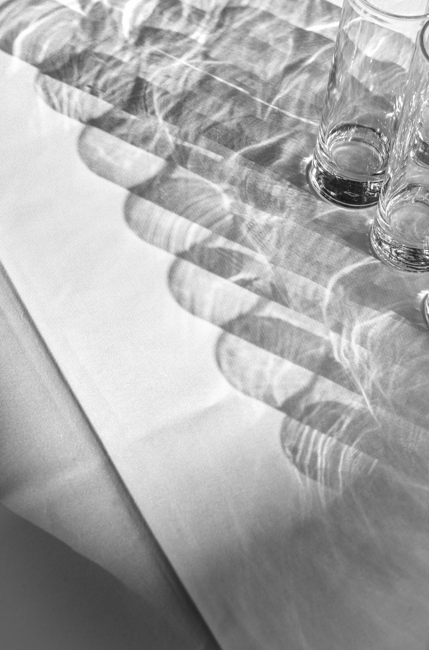 Close-up of white tablecloth and glassware settings in soft focus.