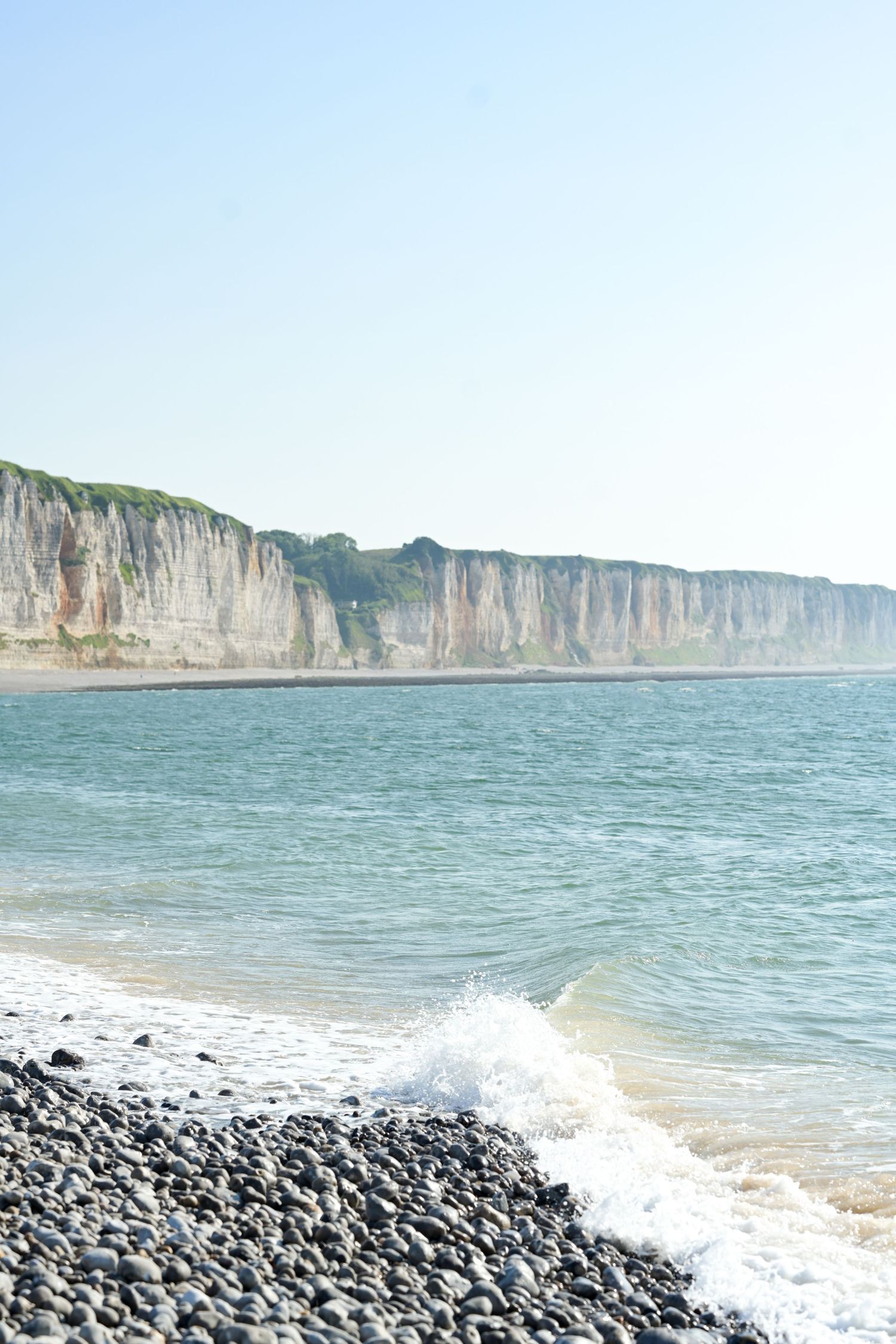 Rocky beach with white chalk cliffs and turquoise waters creating a dramatic coastal landscape.