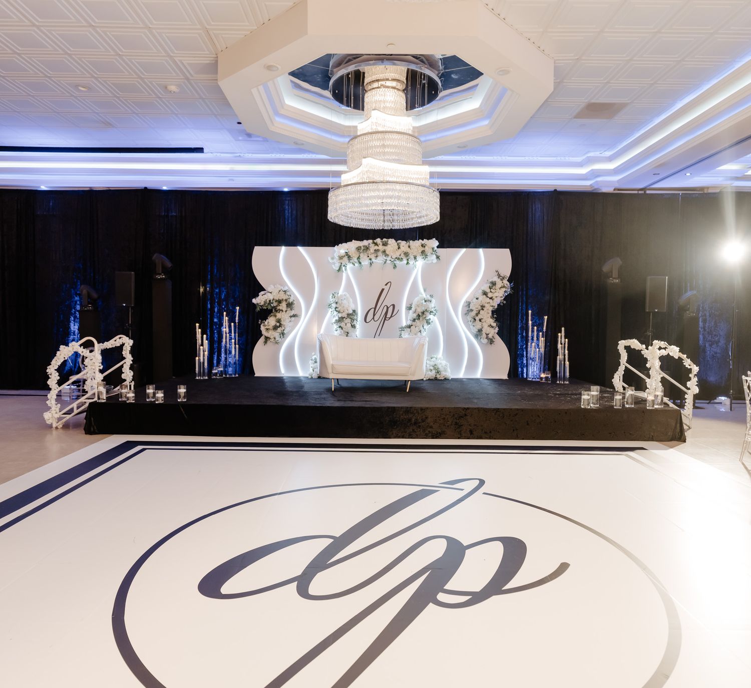 Elegant ballroom venue with white decor and dramatic lighting creating a luxurious wedding reception atmosphere.