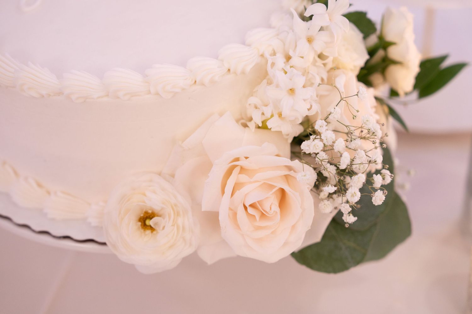 Delicate peach roses and white floral arrangements with greenery decorate a wedding venue.