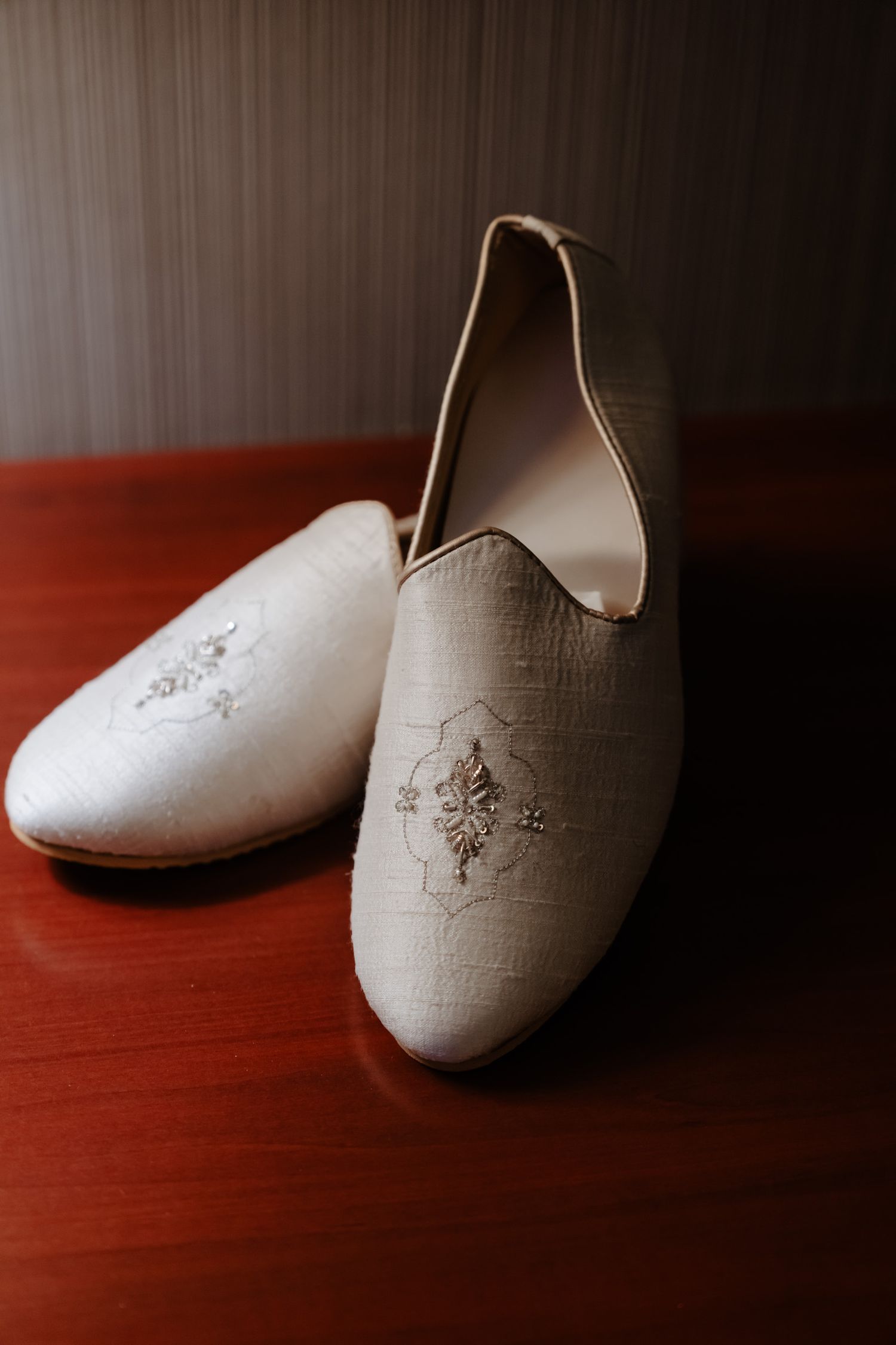 A sequence of artistic shots showing white traditional slippers on a dark wooden surface in different compositions.