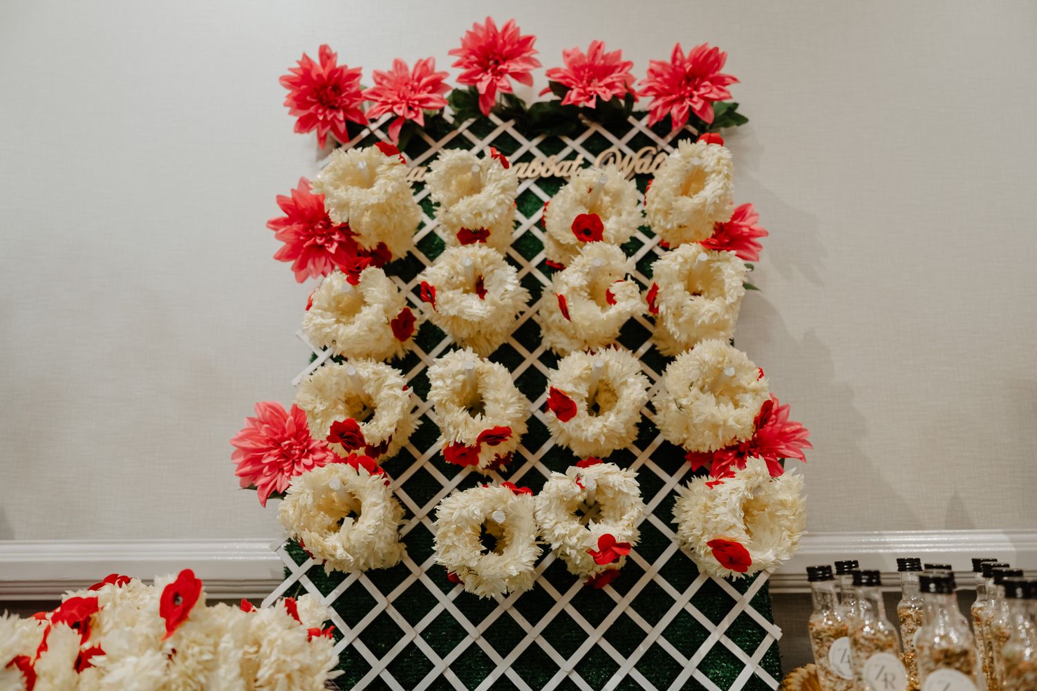 Decorative display featuring white ceramic vases adorned with bright red flowers against a lattice backdrop.