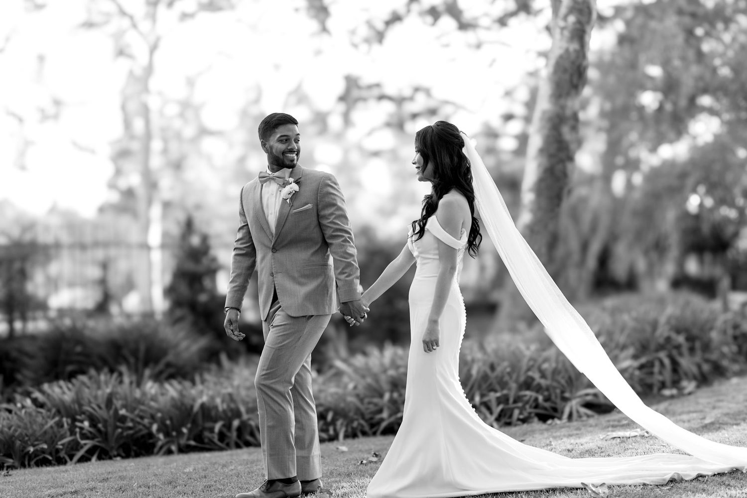 Wedding couple shares romantic moment with flowing veil in garden setting.