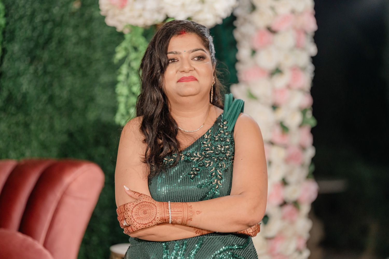 Wedding reception decor featuring emerald green dress against floral backdrop.