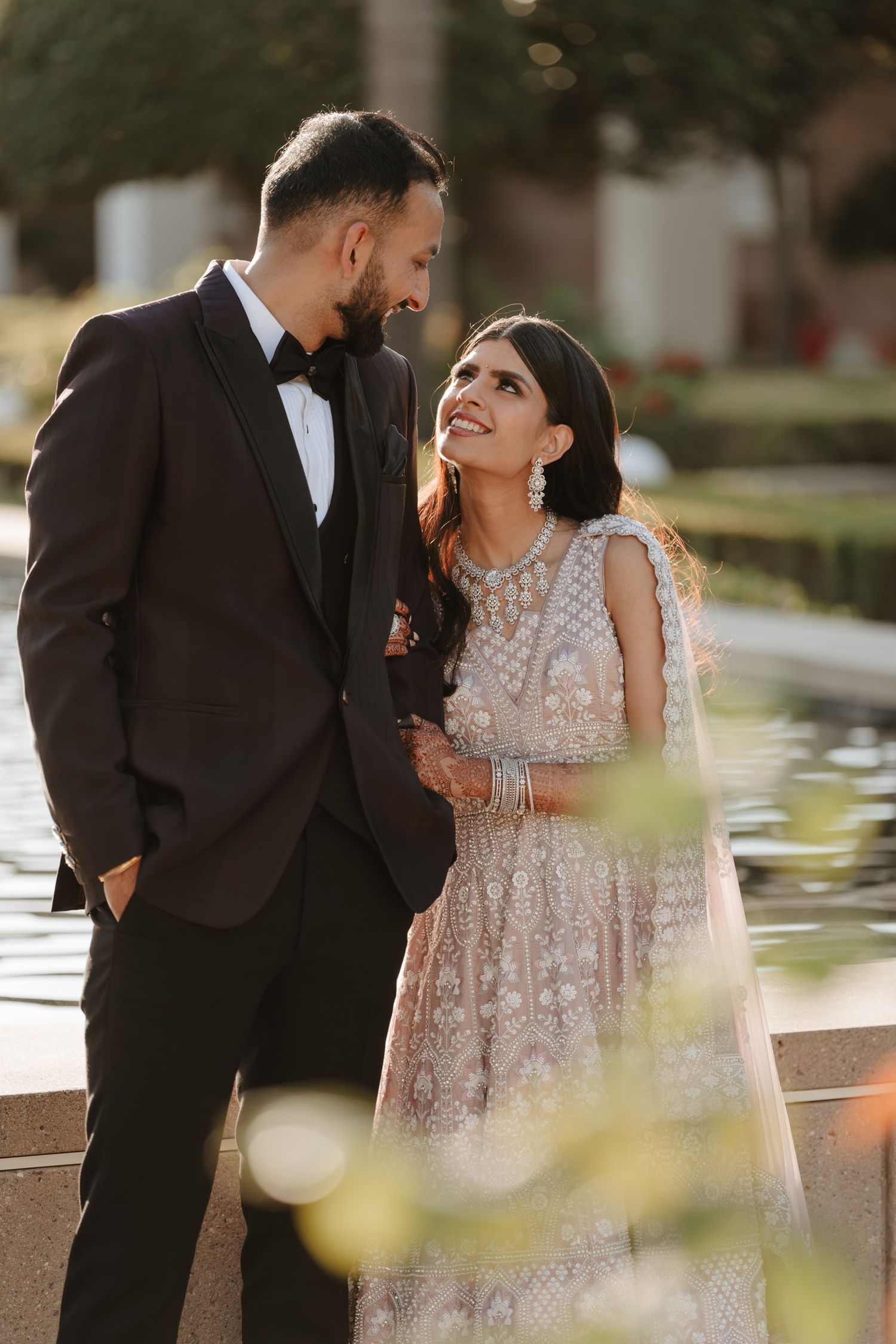 A couple shares intimate moments during their wedding photoshoot in an outdoor garden setting.