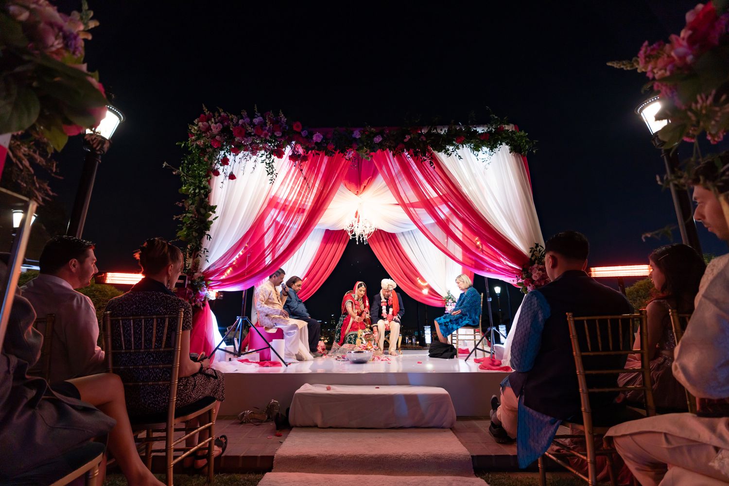 A series of outdoor wedding reception photos showing pink and white draped tents with elegant lighting at night.