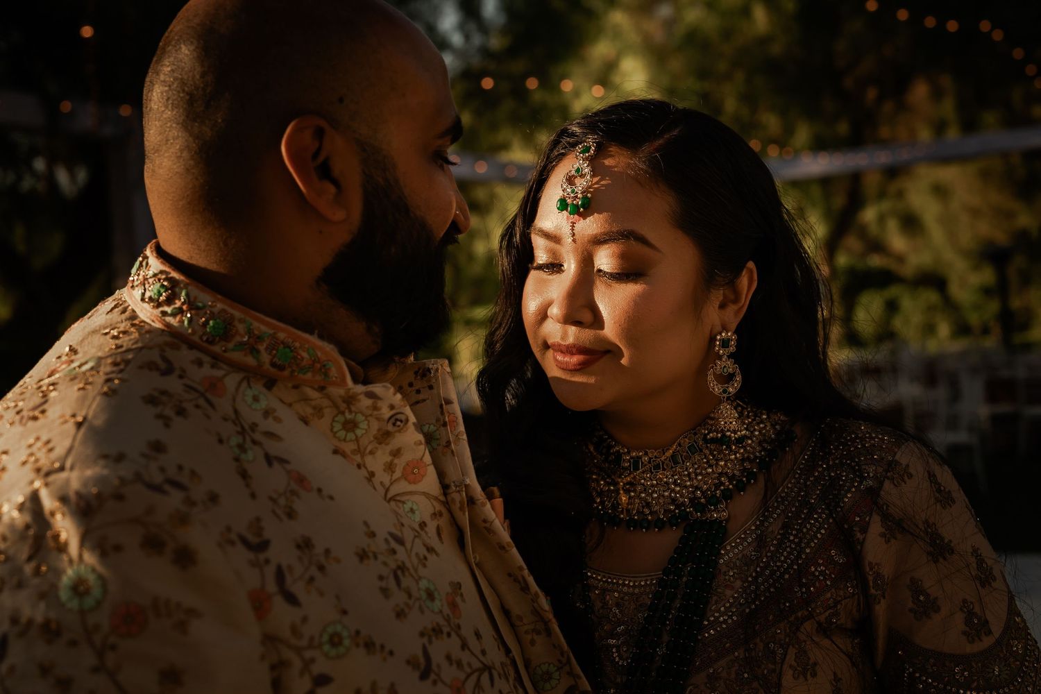 Intimate outdoor wedding ceremony captured in warm evening light with natural garden backdrop.