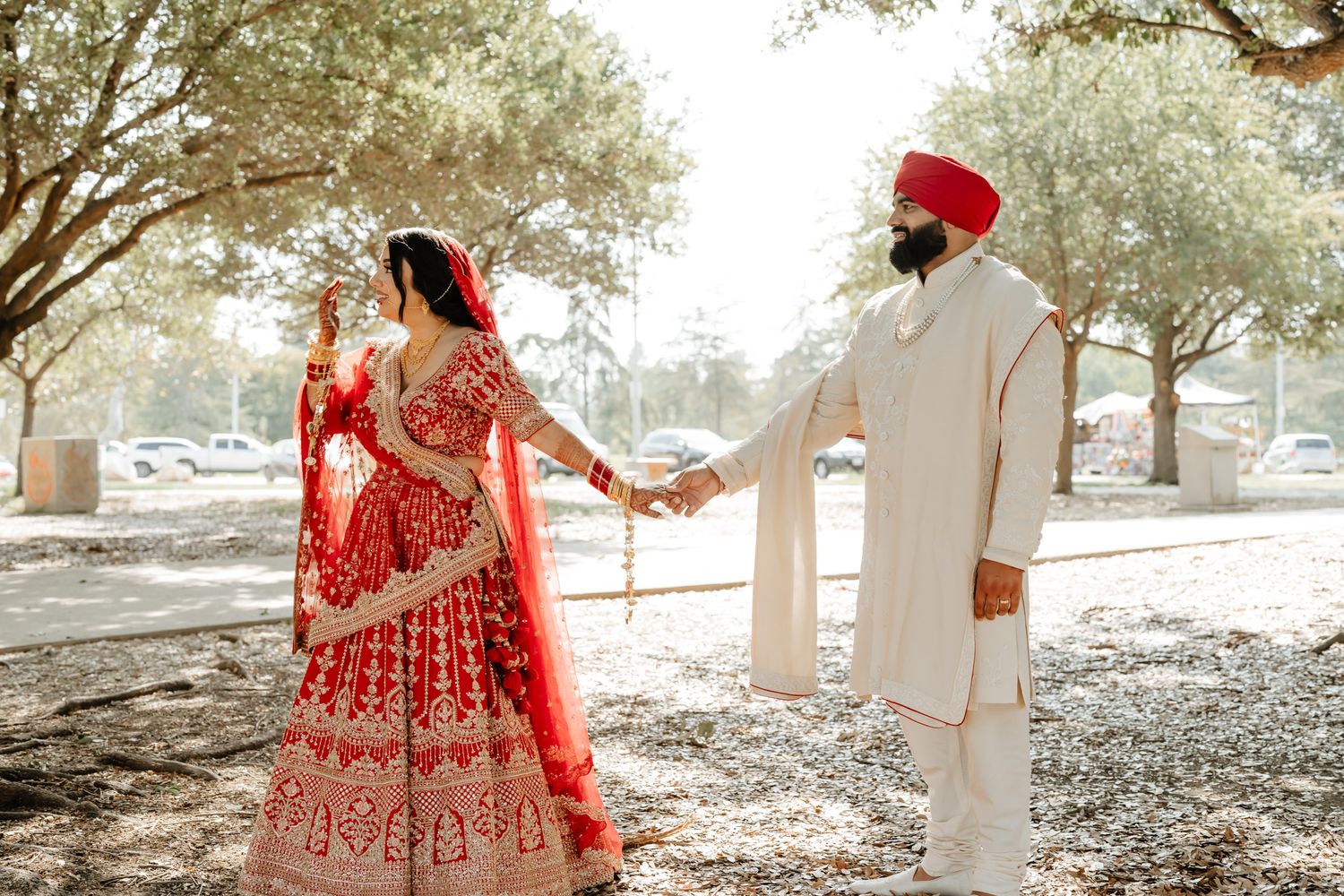 Outdoor wedding photography session under trees with traditional Indian wedding attire.