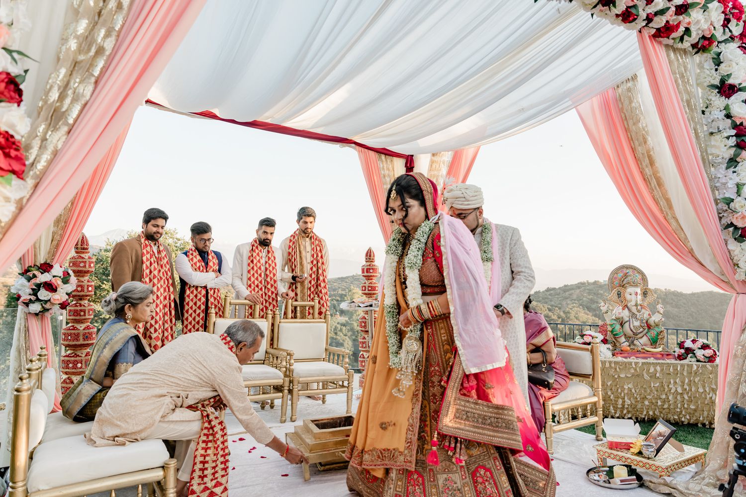 Outdoor wedding ceremony setup with pink and white draped fabric canopy and floral decorations.