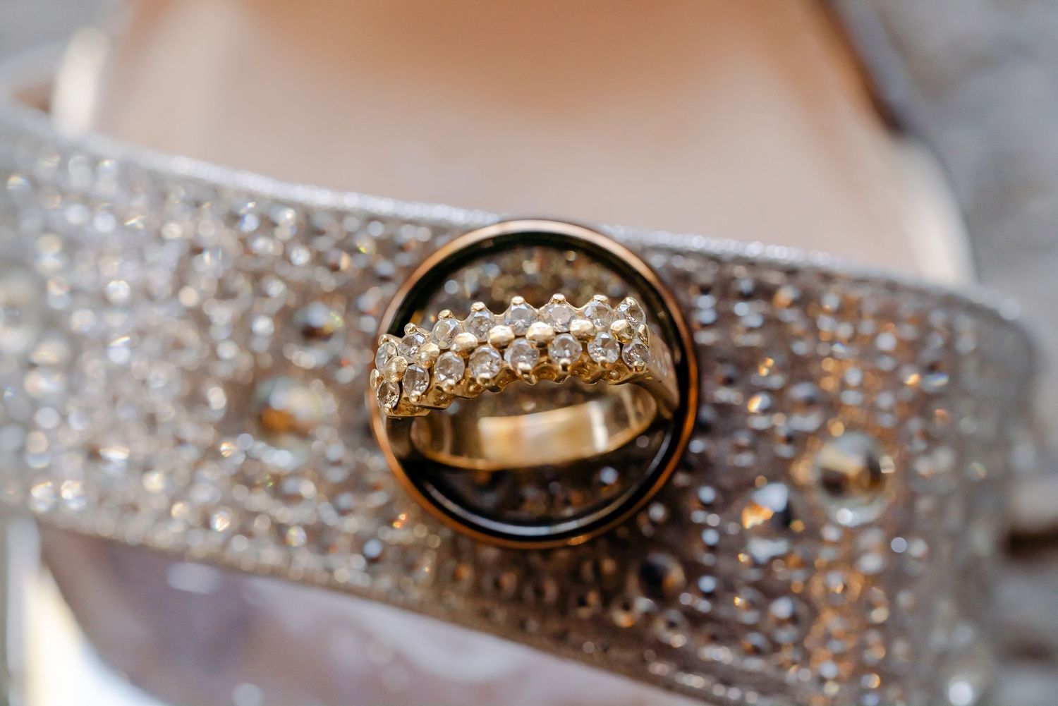 Wedding rings and jewelry sparkle with diamonds and precious metals against a light textured background.