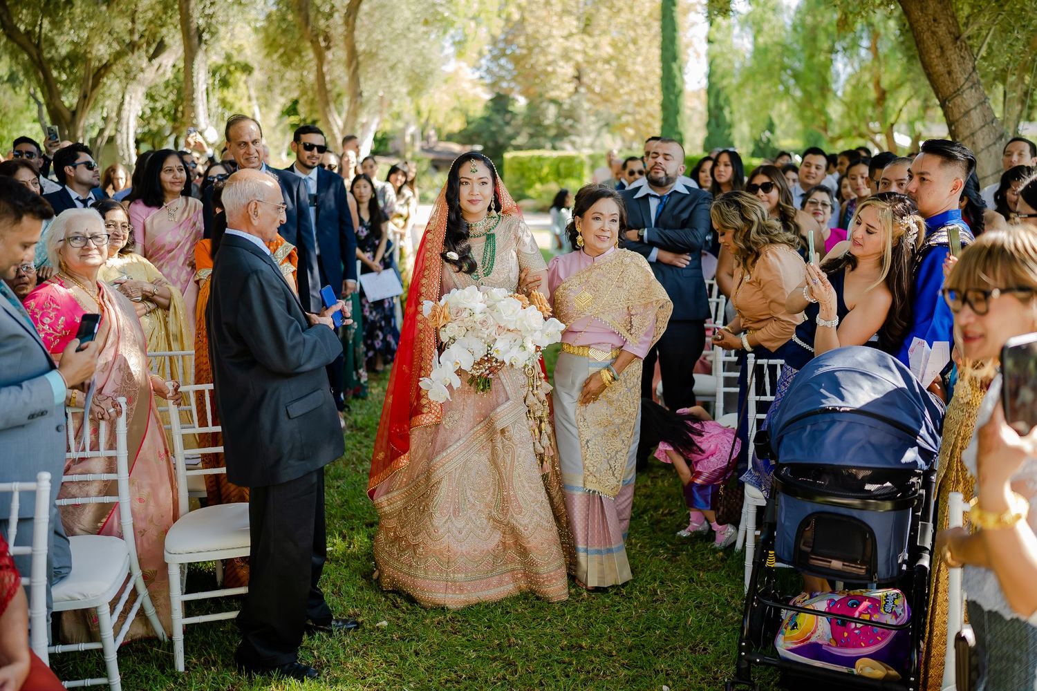 Wedding guests seated outdoors enjoying a celebration under trees with natural lighting.