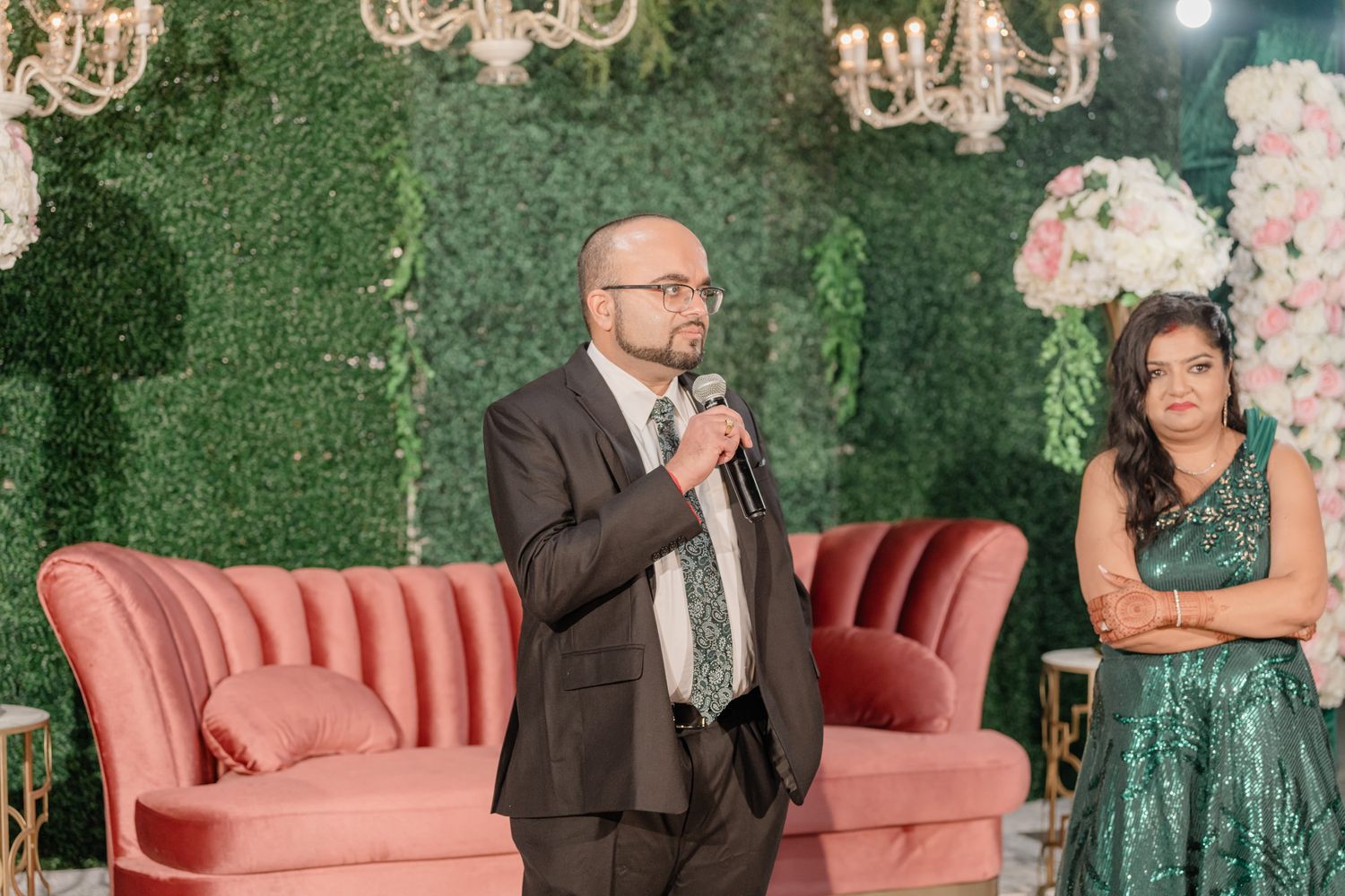 Wedding reception seating area with pink vintage couch against green floral wall.