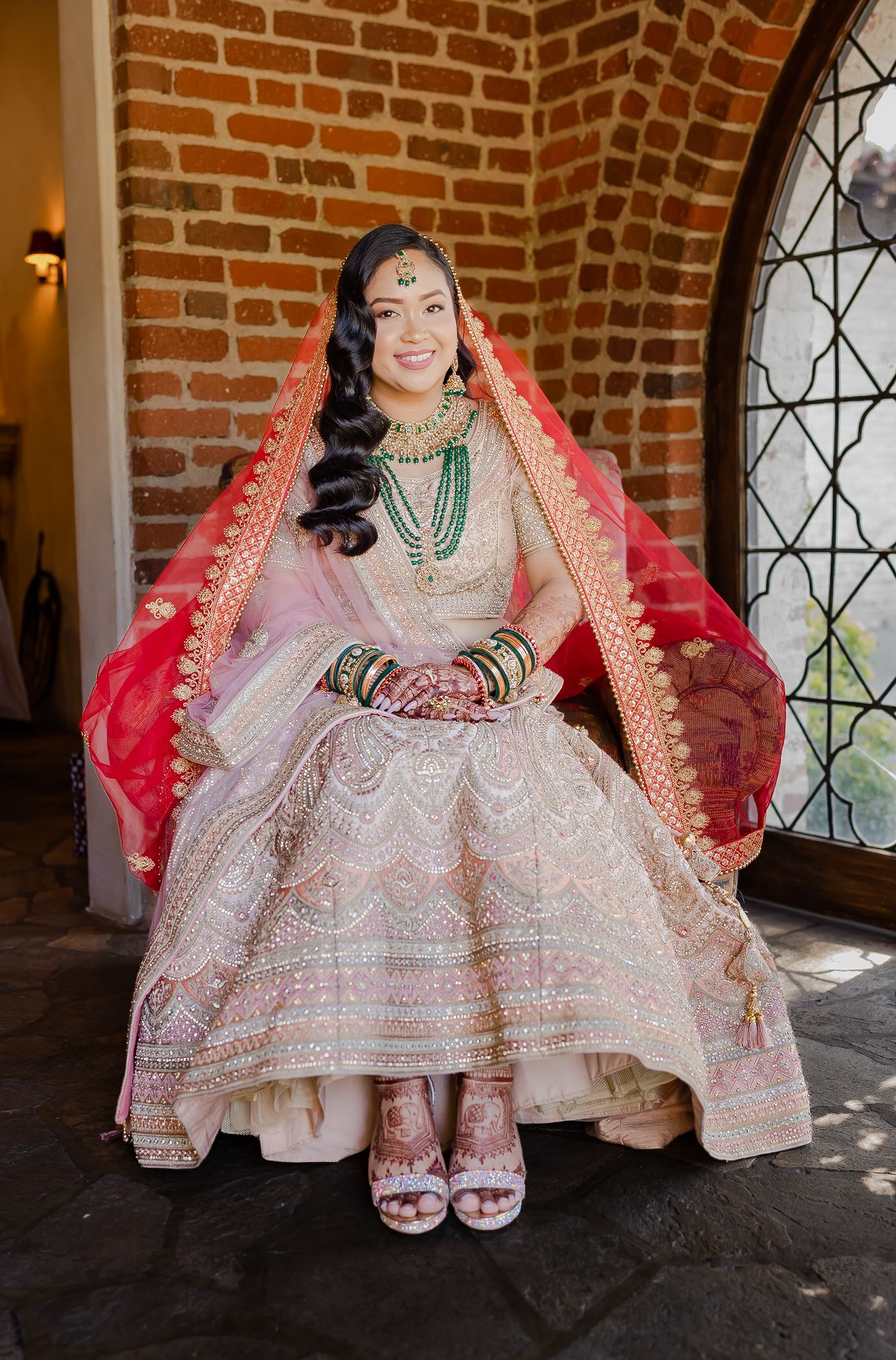 Traditional Indian bridal attire featuring an ornate white and pink lehenga with intricate embroidery and red dupatta.