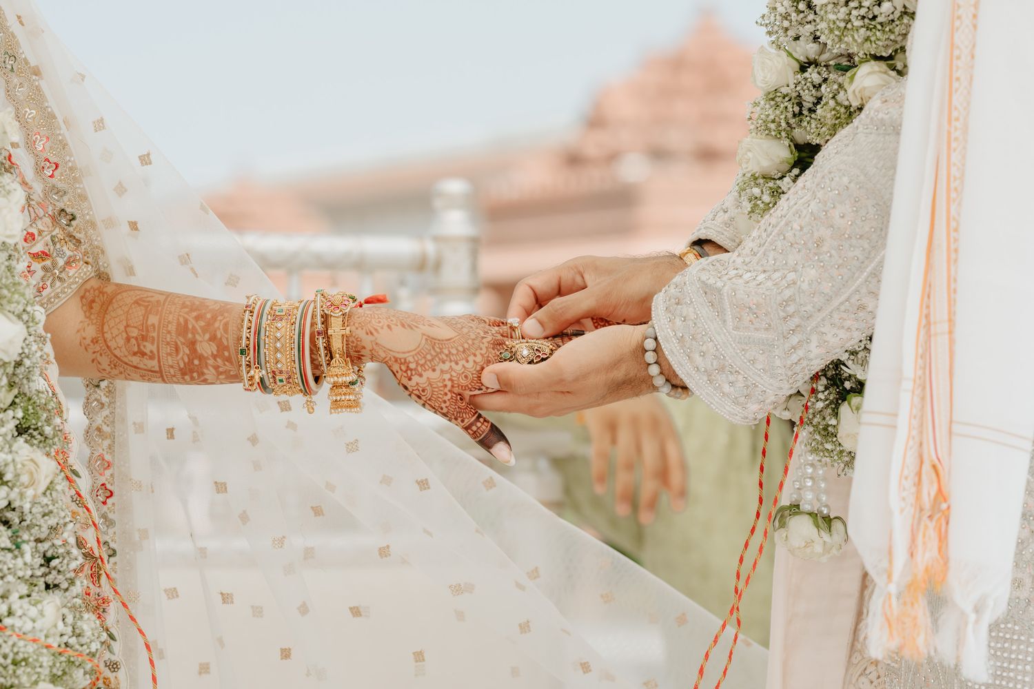 Wedding ceremony details showing hands and traditional Indian wedding decorations.