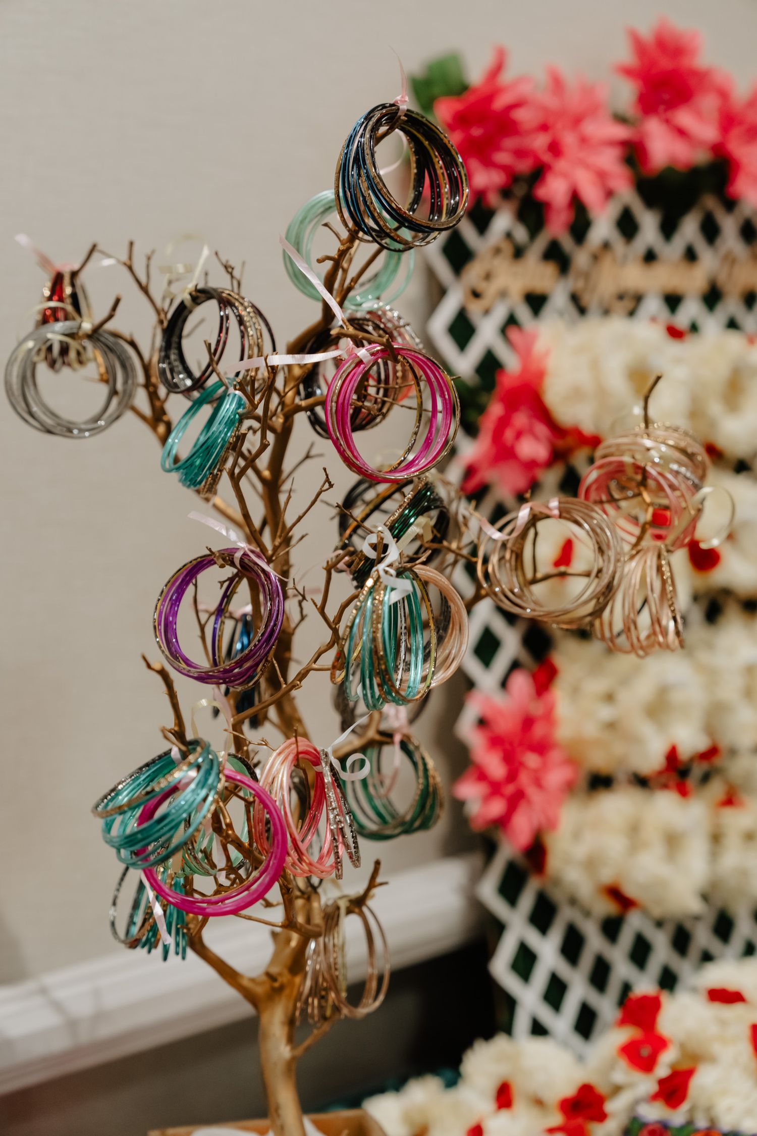 Colorful jewelry display tree with bangles and bracelets in turquoise, pink, and gold tones.