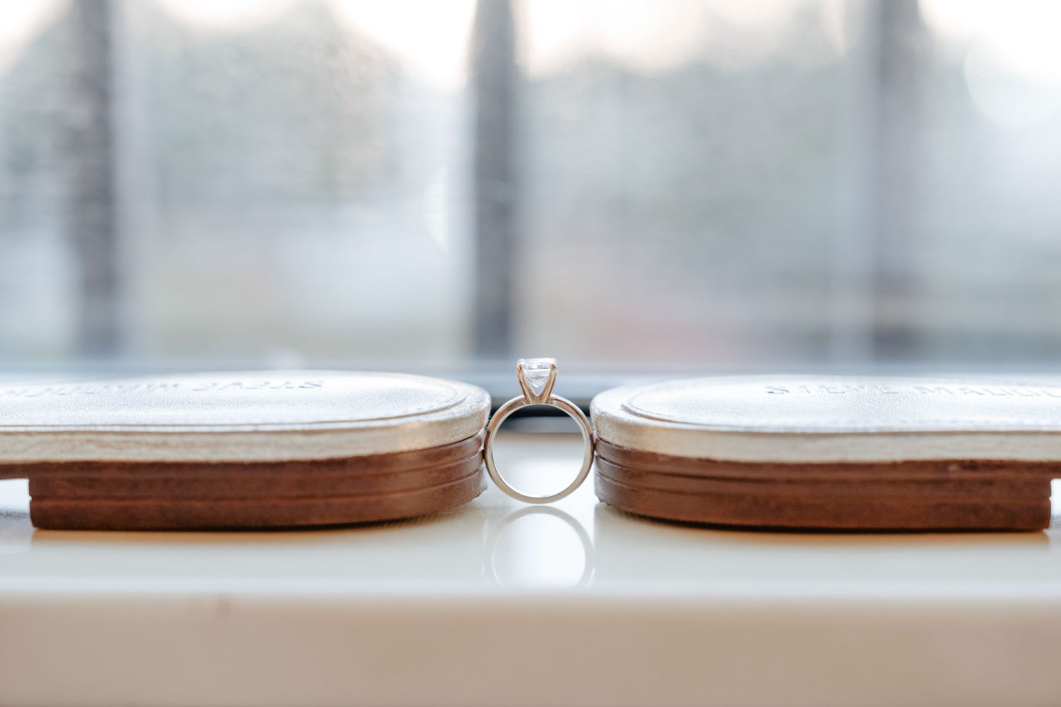 A close-up view of wooden coasters with metal handles arranged in a neat stack on a white surface.