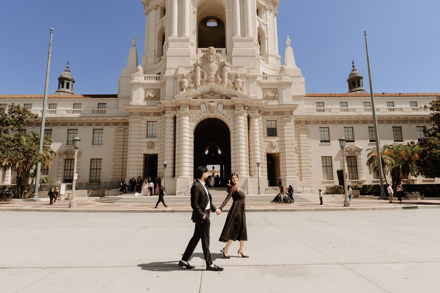 Couple walking in front of Pasadena City Hall on a sunny day, elegant architecture backdrop.