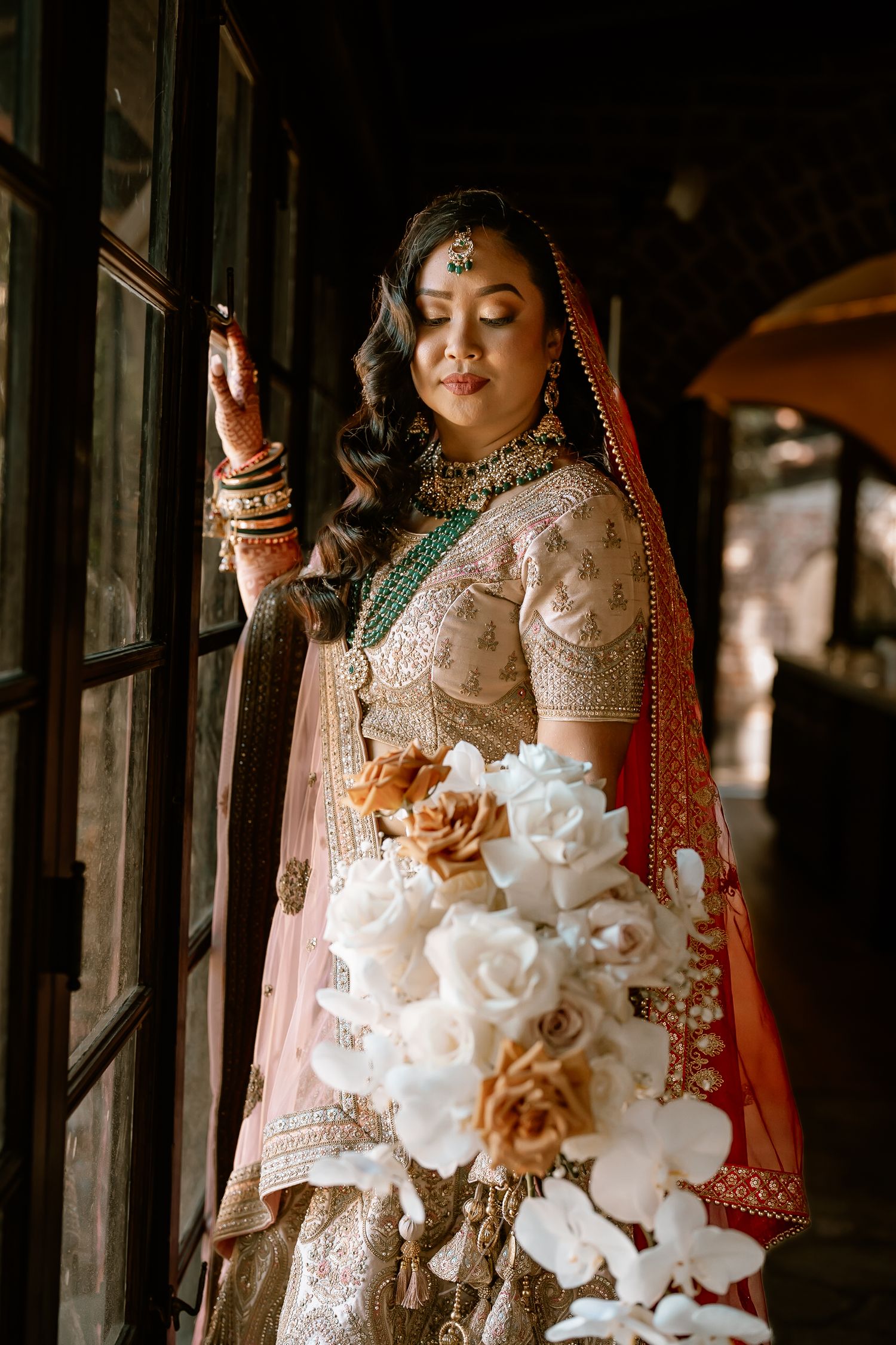 White floral bouquet with roses held against traditional Indian bridal attire.