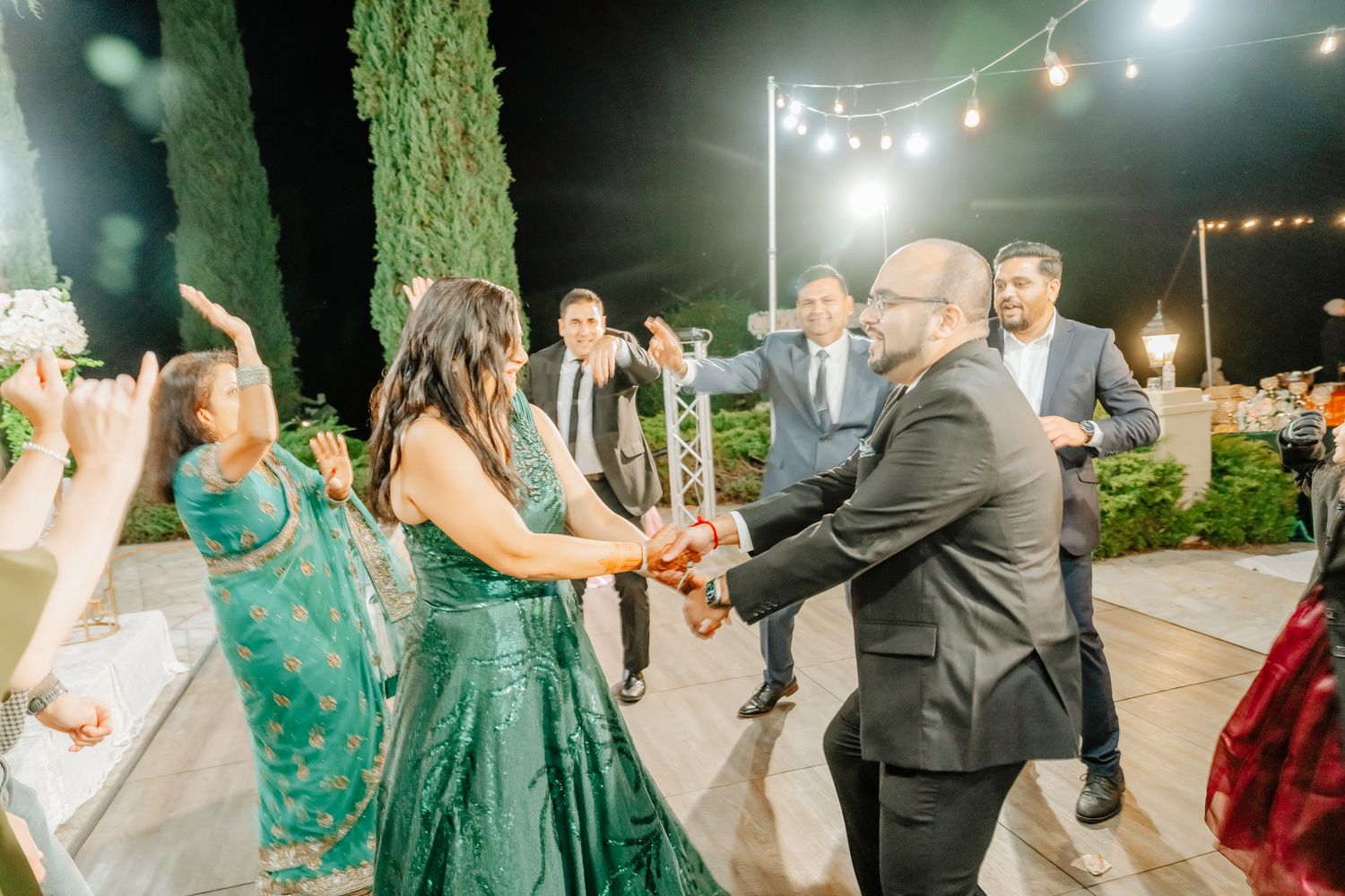 Outdoor evening celebration with string lights and guests dancing on a patio.