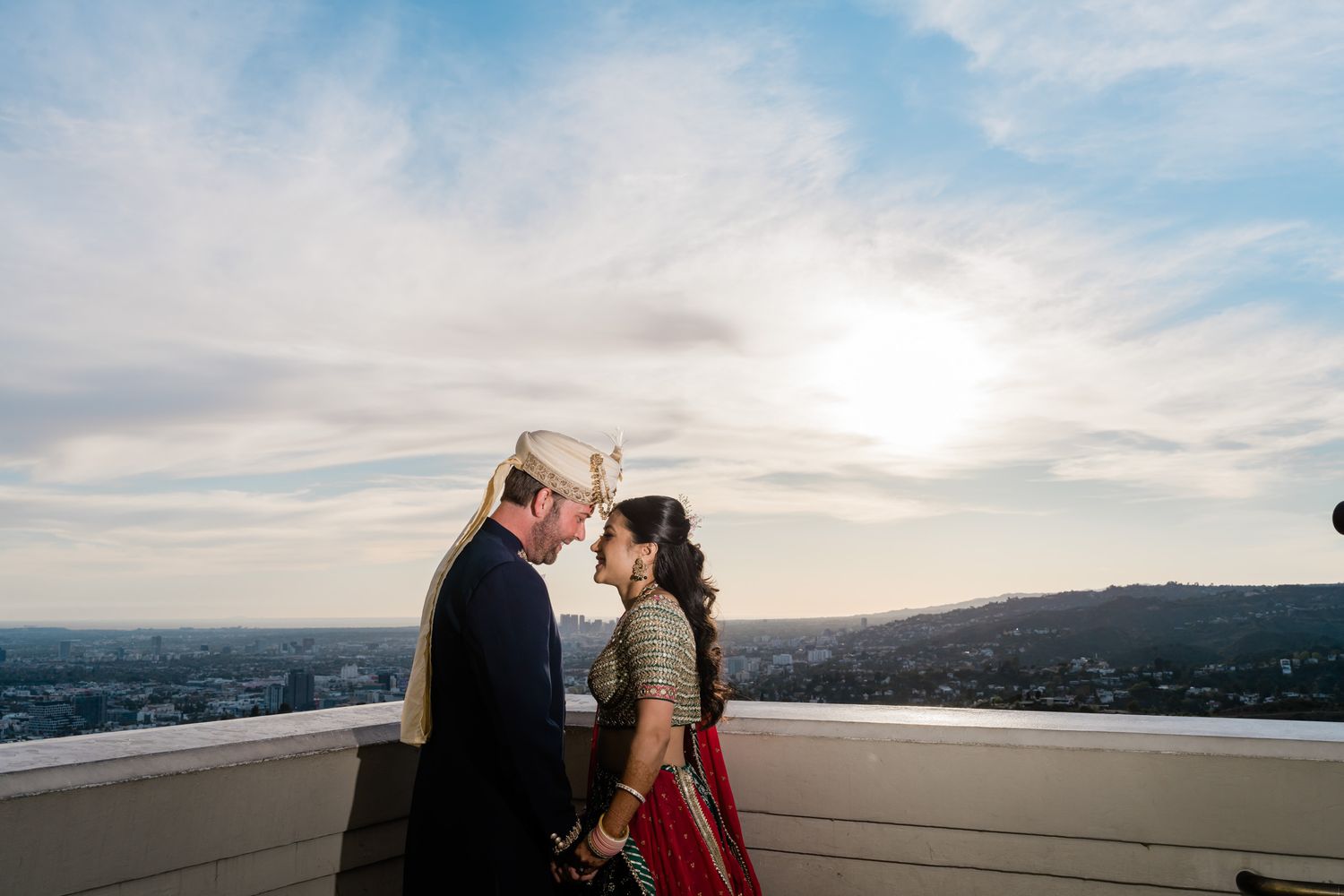 Romantic sunset photoshoot with city skyline and ocean views in the background.