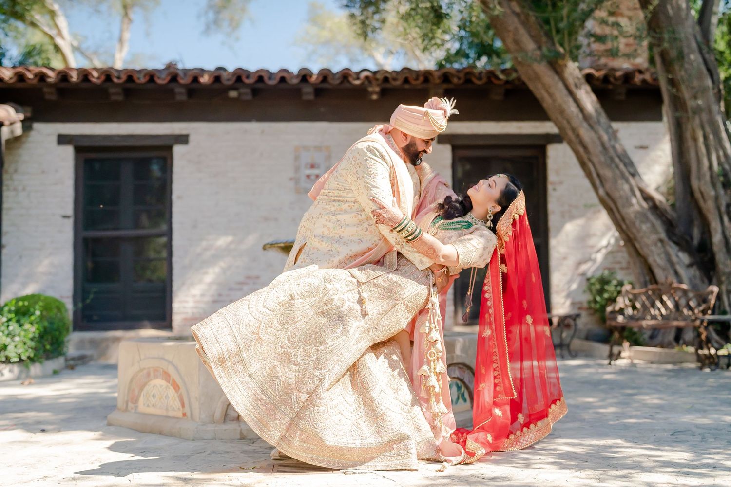Elegant outdoor wedding ceremony setup with floral arrangements and white chairs under shady trees.