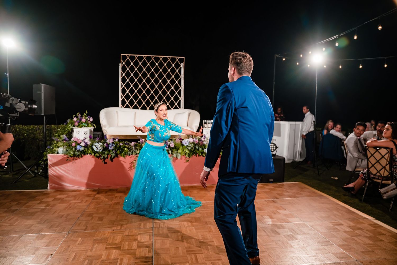 Wedding reception dance floor with couples dancing under nighttime lighting with decorative lattice panels visible.