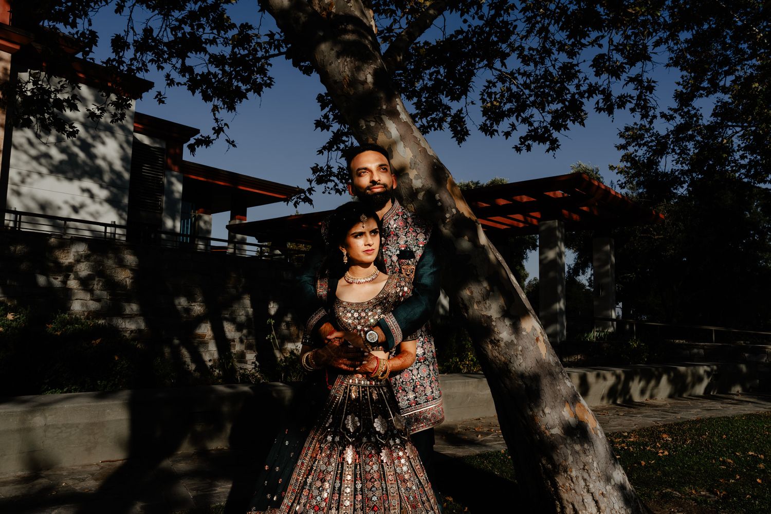 Dramatic outdoor portrait session with traditional wedding attire against evening sky.