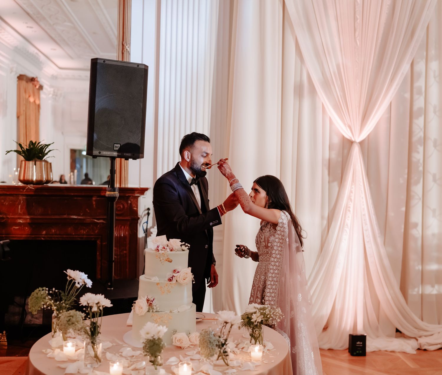 Romantic couple shares a dance in an elegant white and blush wedding reception venue.