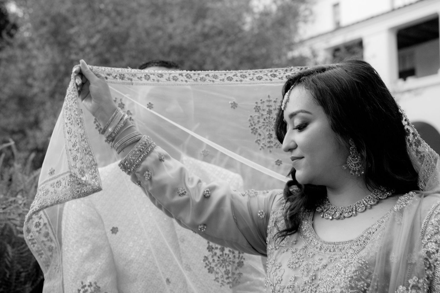 Artistic bridal portraits with flowing veil and lace details against architectural elements.