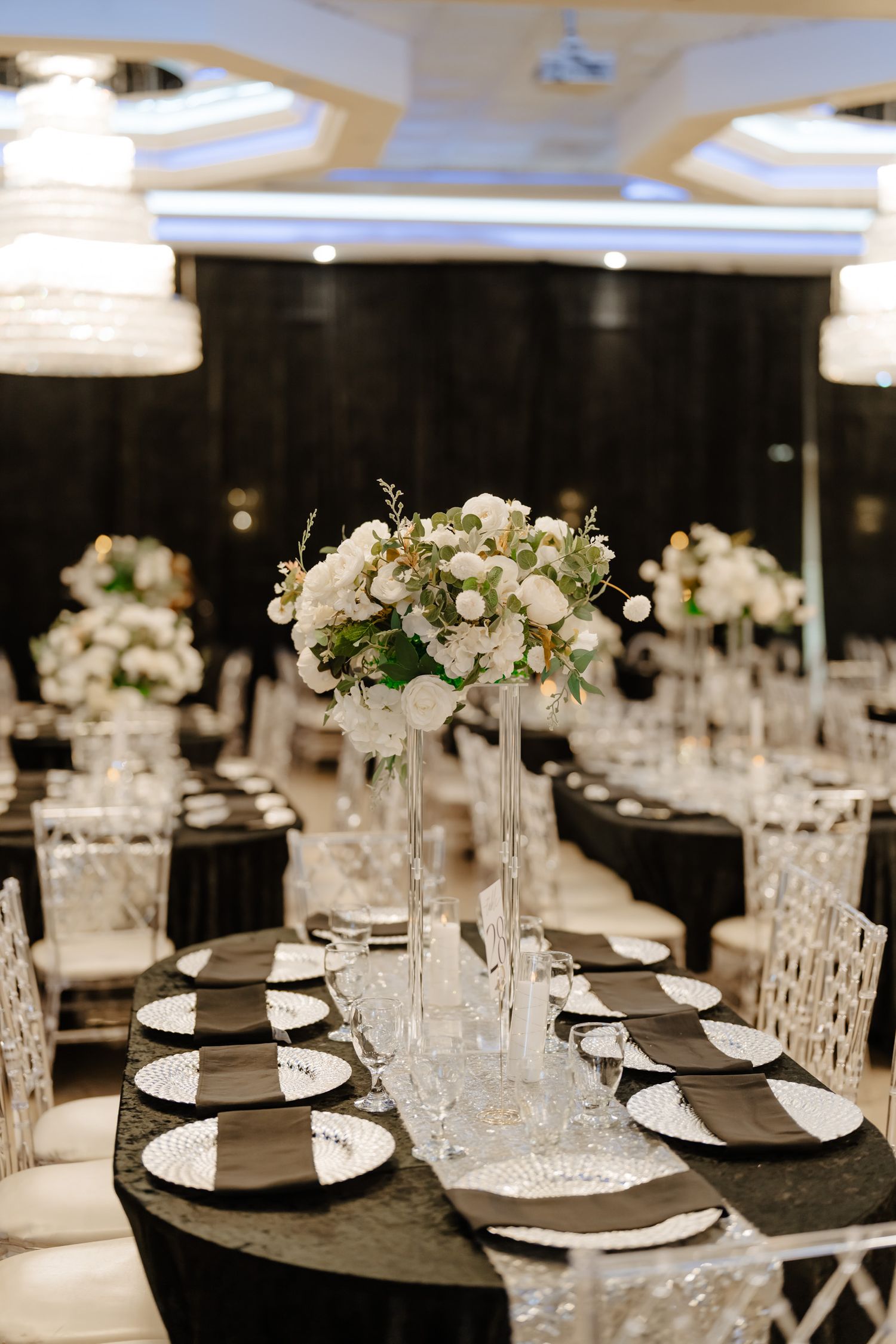 Elegant wedding reception tables set with white floral centerpieces and crystal glassware.