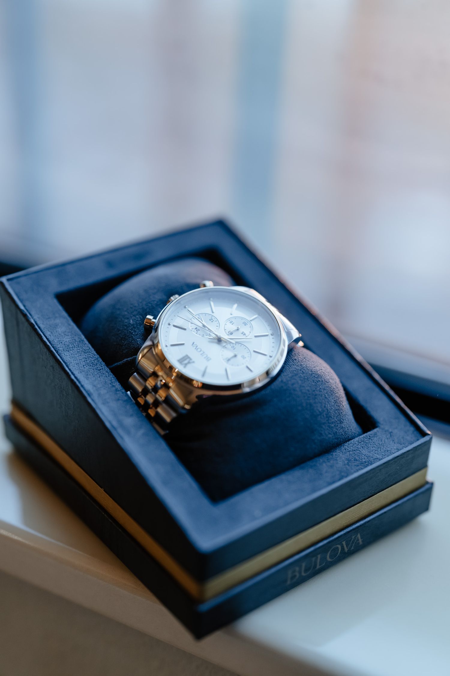 Multiple views of an elegant silver wristwatch displayed in a black presentation box.